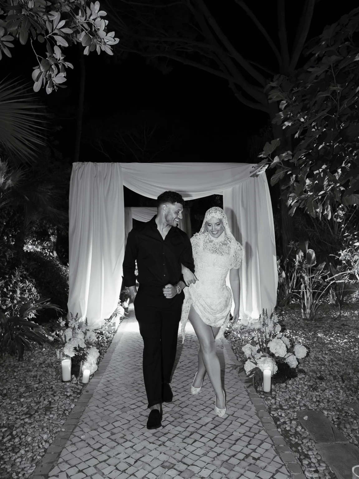 Perrie and Alex walking together after dark in black and white