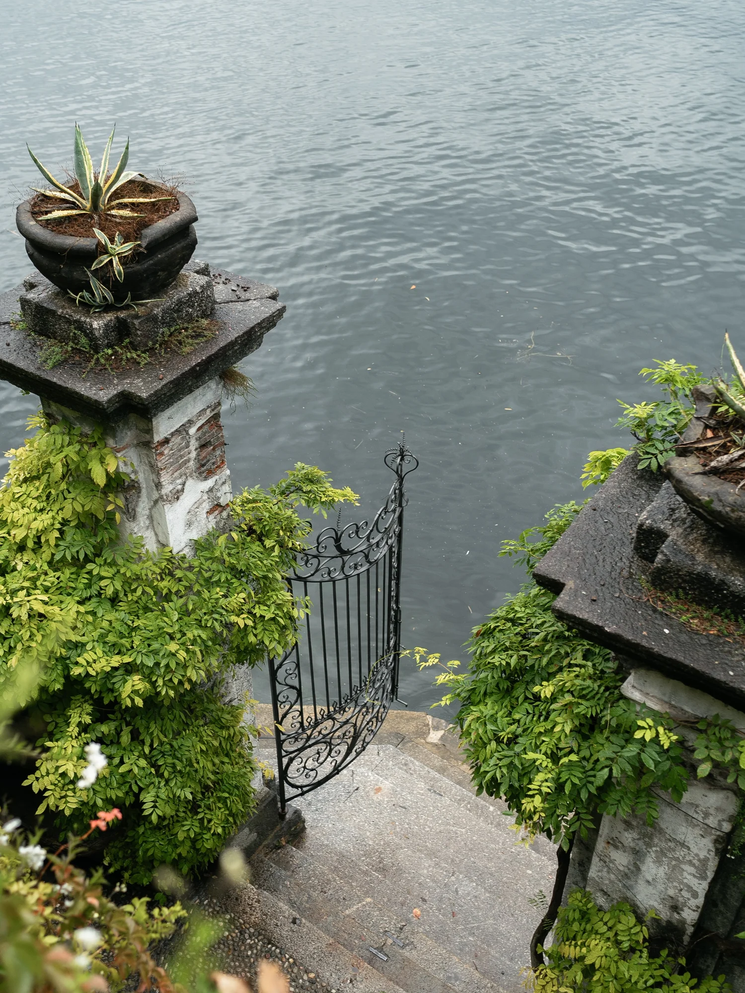 Ornate iron garden gate and stone steps leading down to the water