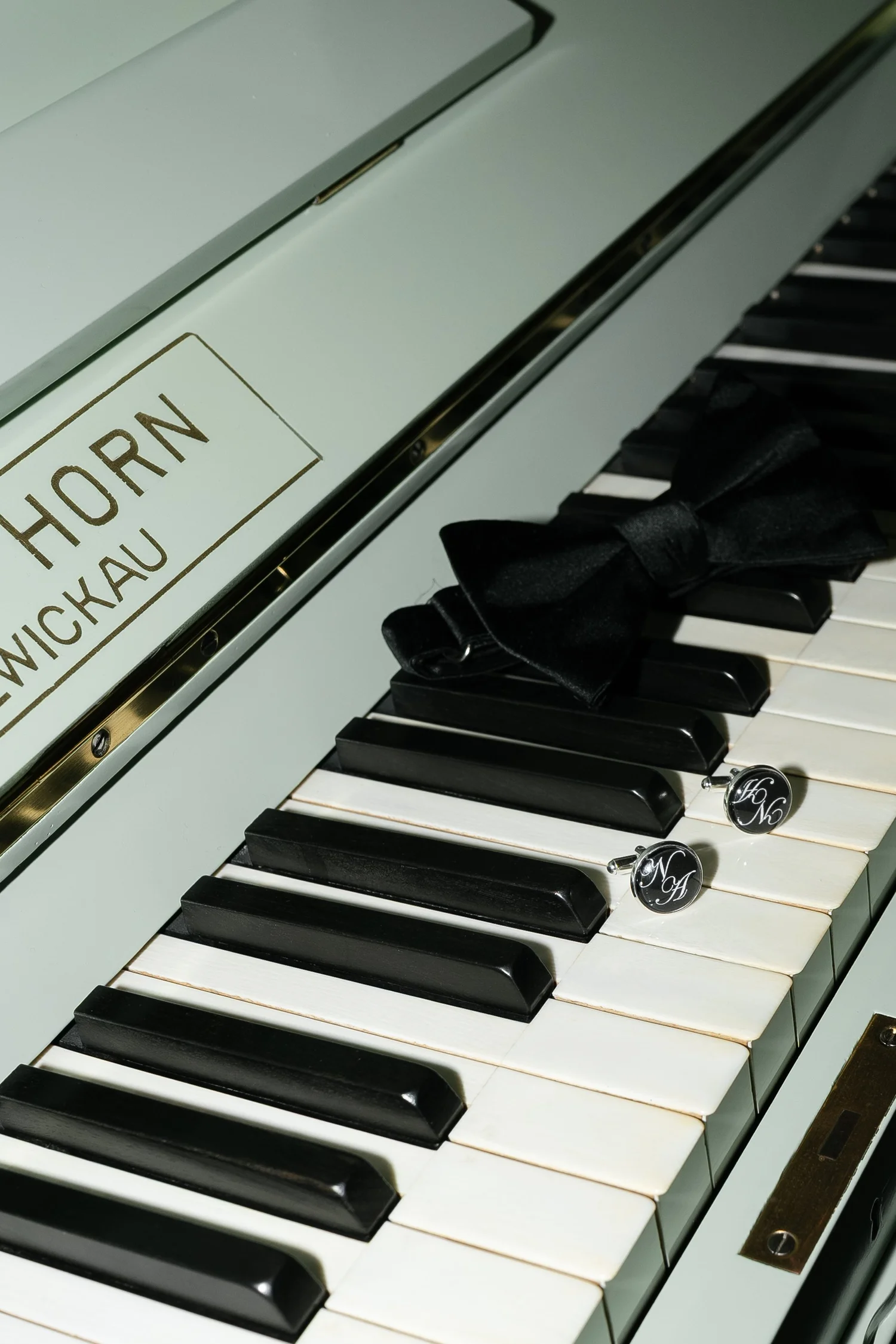 Groom’s black bow tie and cufflinks arranged on white piano keys
