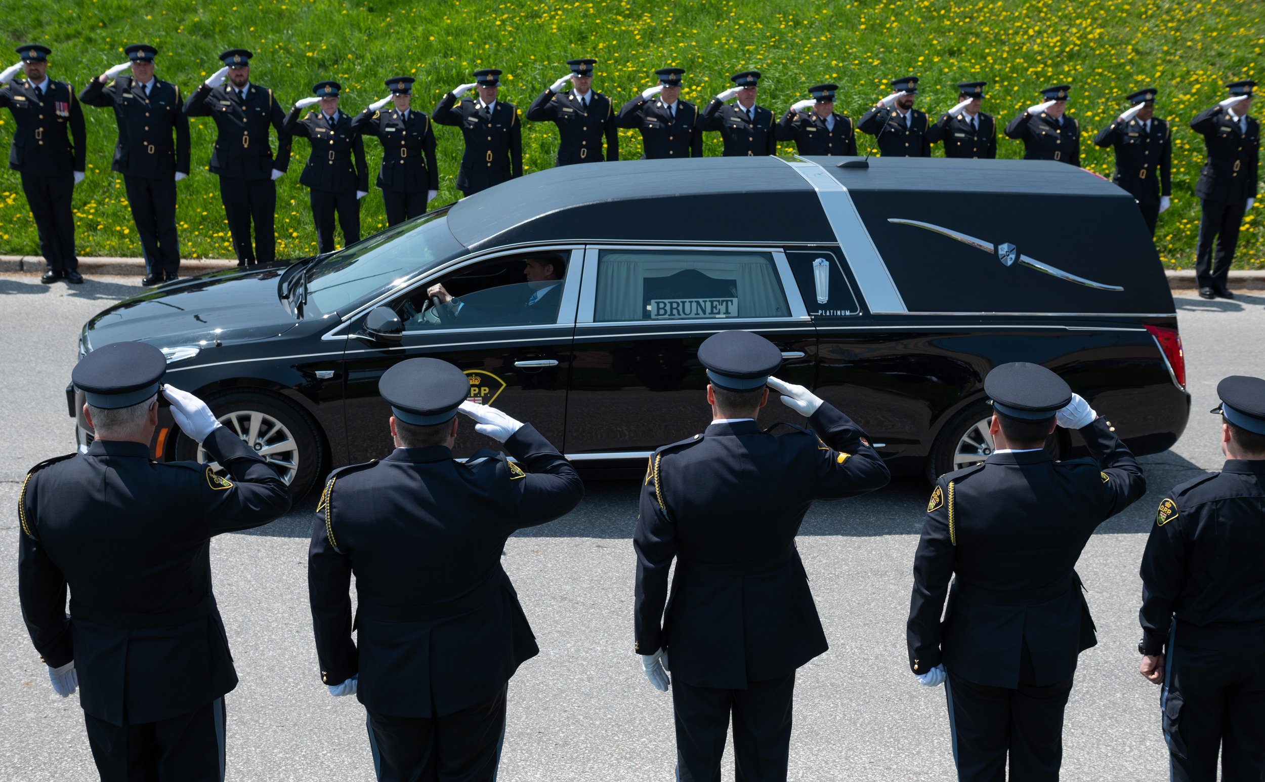  Members of the Ontario Provincial Police salute as the vehicle carrying OPP Sgt. Eric Mueller leaves the grounds of the Canadian Tire Centre following a funeral in Ottawa, on Thursday, May 18, 2023. THE CANADIAN PRESS/Spencer Colby 