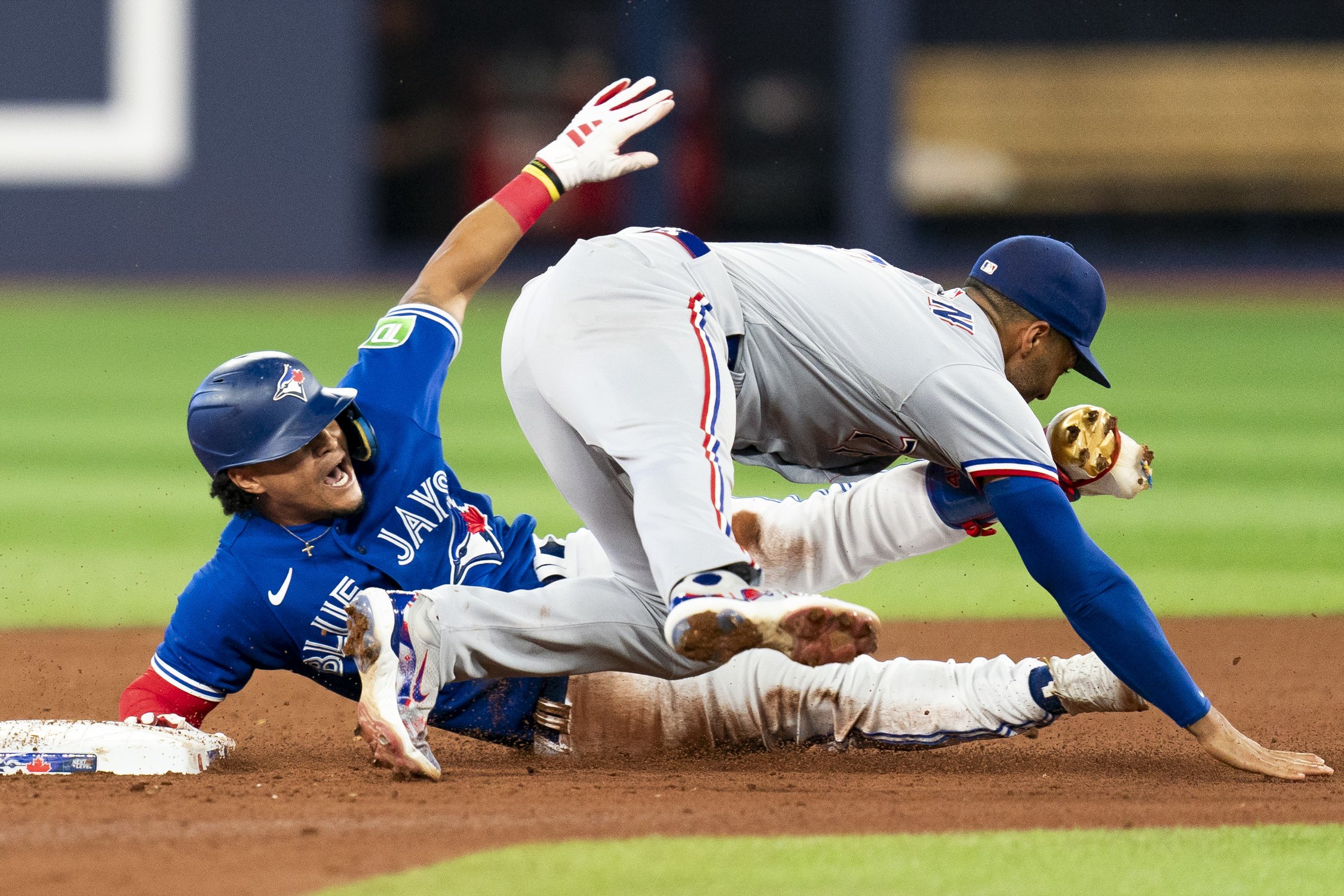  Toronto Blue Jays second baseman Santiago Espinal (5) safely slides to second base as Texas Rangers second baseman Marcus Semien (2) attempts a tag during seventh inning American League MLB baseball action in Toronto, on Tuesday, Sept. 12, 2023. THE