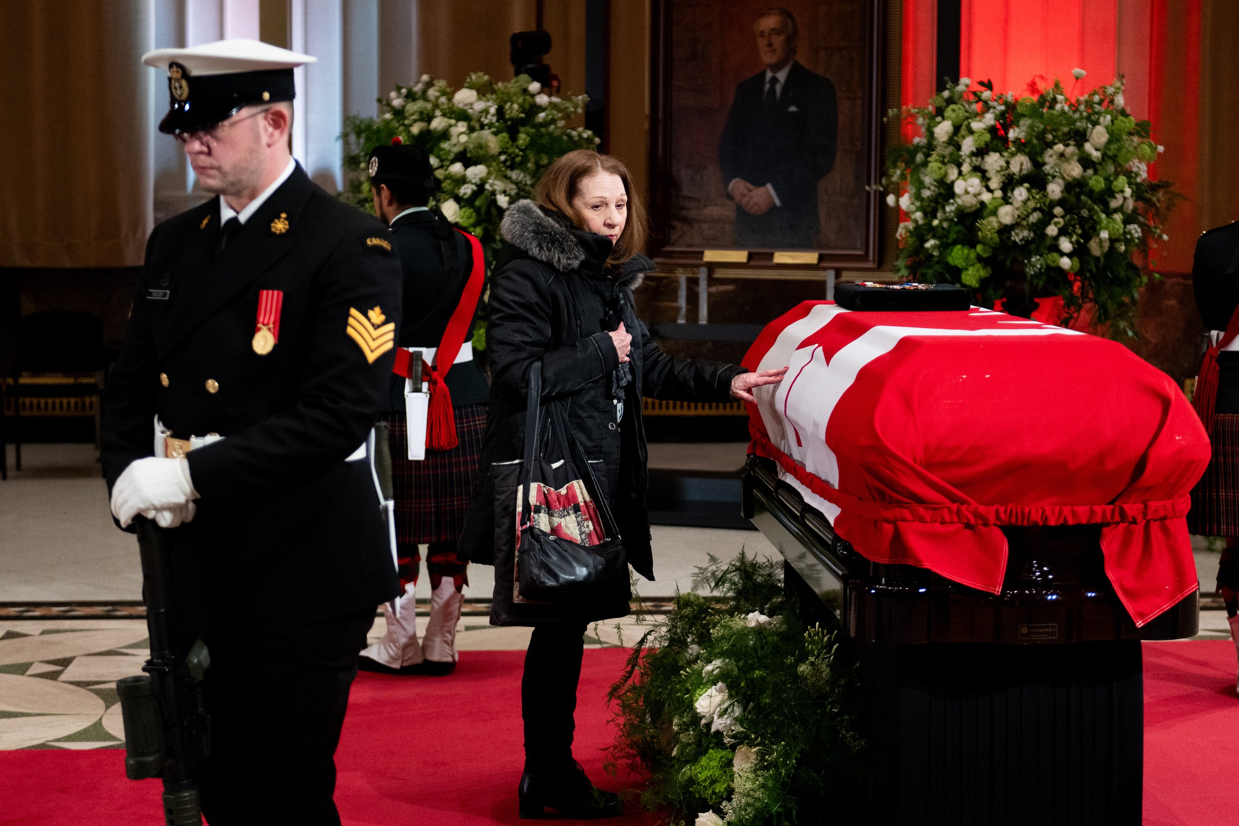  A well wisher places their hand on the casket of former prime minister Brian Mulroney as he lies in state at the Sir John A. Macdonald Building, across from Parliament Hill in Ottawa, on Tuesday, March 19, 2024. THE CANADIAN PRESS/Spencer Colby 