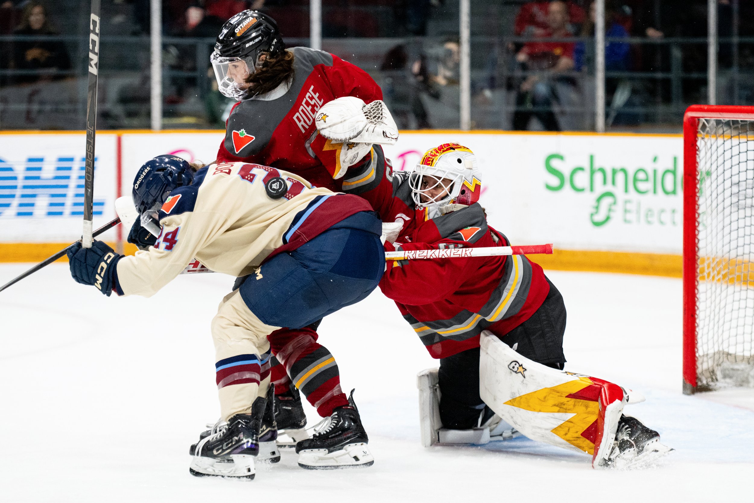 Ottawa Charge goaltender Gwyneth Philips (33) reaches over teammate Jincy Roese (71) and Montreal Victoire's Abigail Boreen (24) to make a save during second period PWHL hockey action in Ottawa, on Saturday, April 26, 2025. THE CANADIAN PRESS/Spence