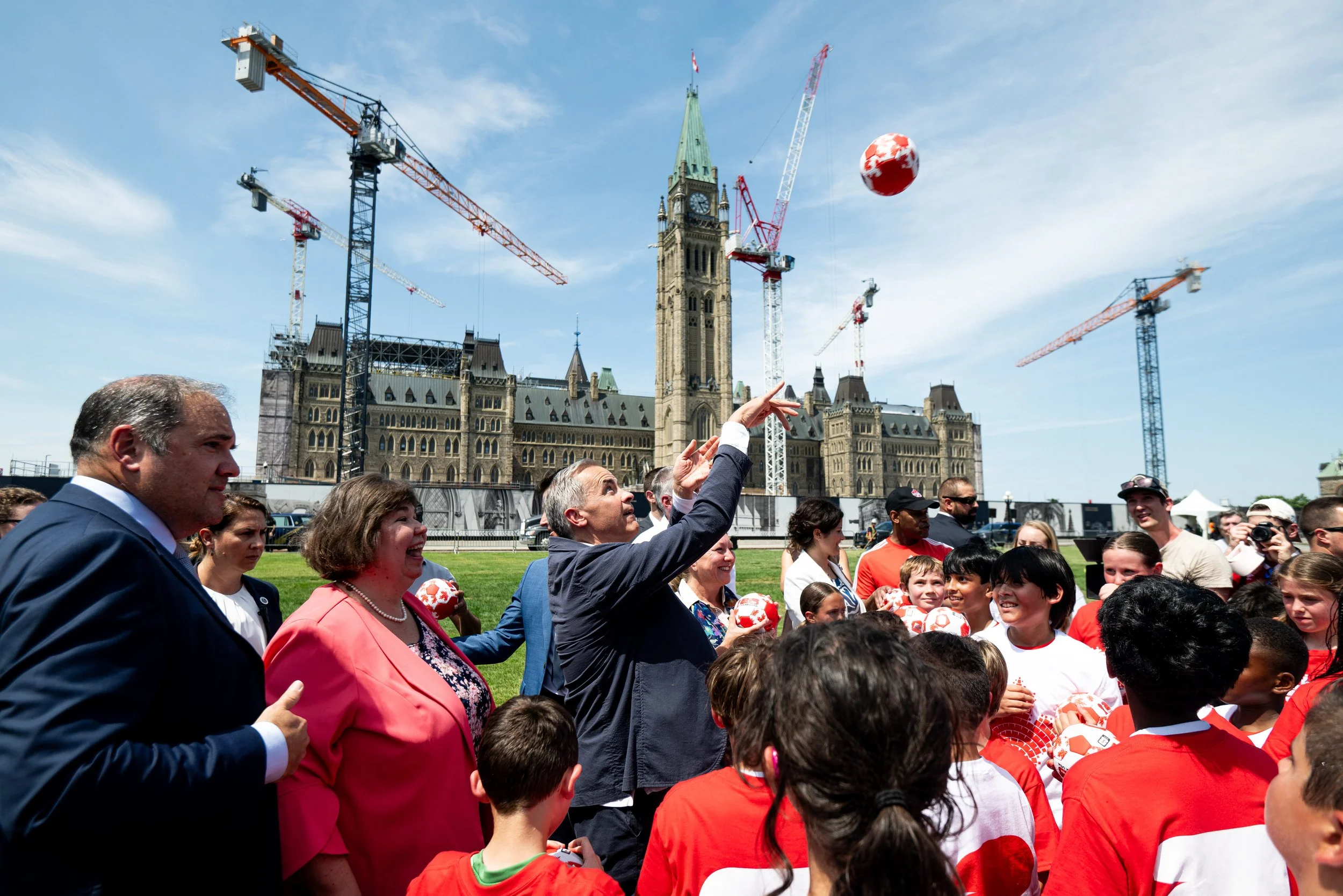  Prime Minister Mark Carney tosses a ball towards kids during a break in a youth soccer game on Parliament Hill marking the upcoming FIFA World Cup championships in Ottawa on Monday, June 30, 2025. THE CANADIAN PRESS/Spencer Colby 
