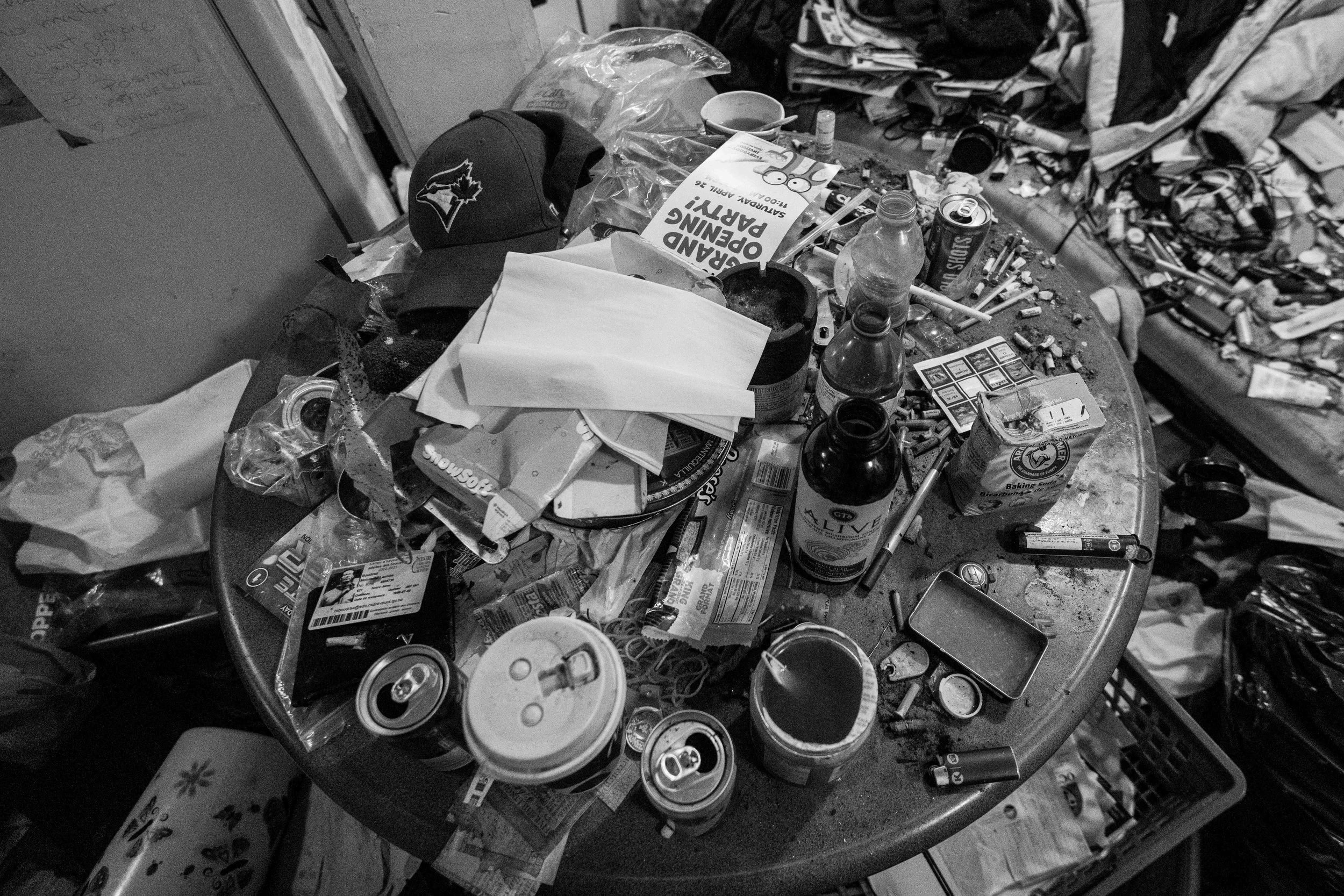  A Toronto Blue Jays hat is pictured atop a table crowded with discarded  drug paraphernalia, trash and various cups filled with urine in Thumper’s living room of her Glebe neighbourhood apartment 