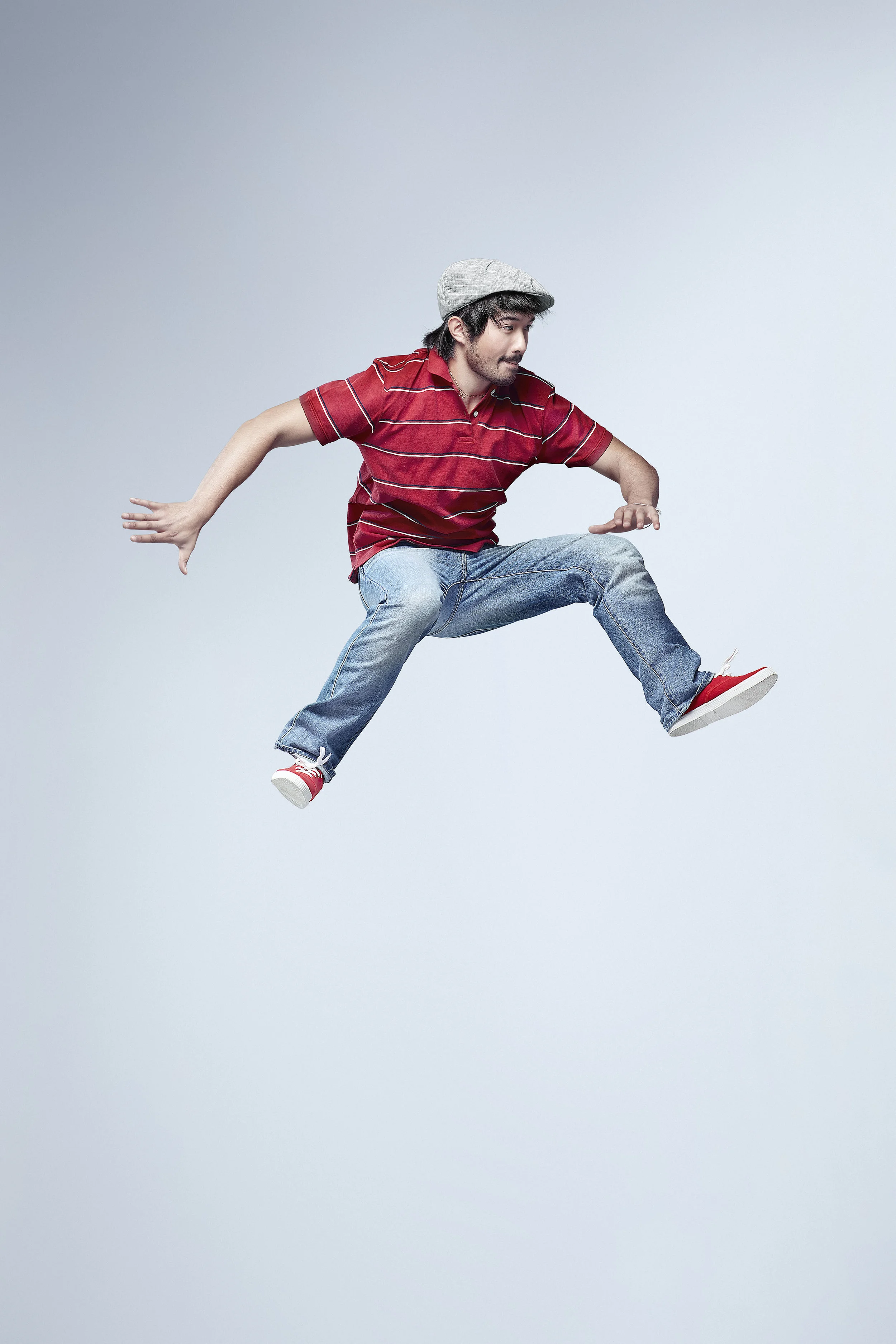 A man in casual clothes appearing to be floating in mid-air against a plain light background.