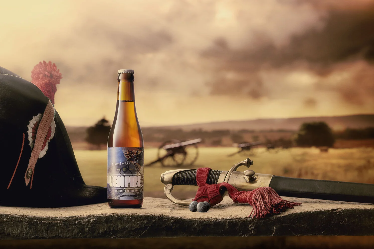 A medieval-inspired scene with a leather armoured helmet, a beer bottle, a sword with a red tassel, and a background of cannons and open farmland under a cloudy sky.