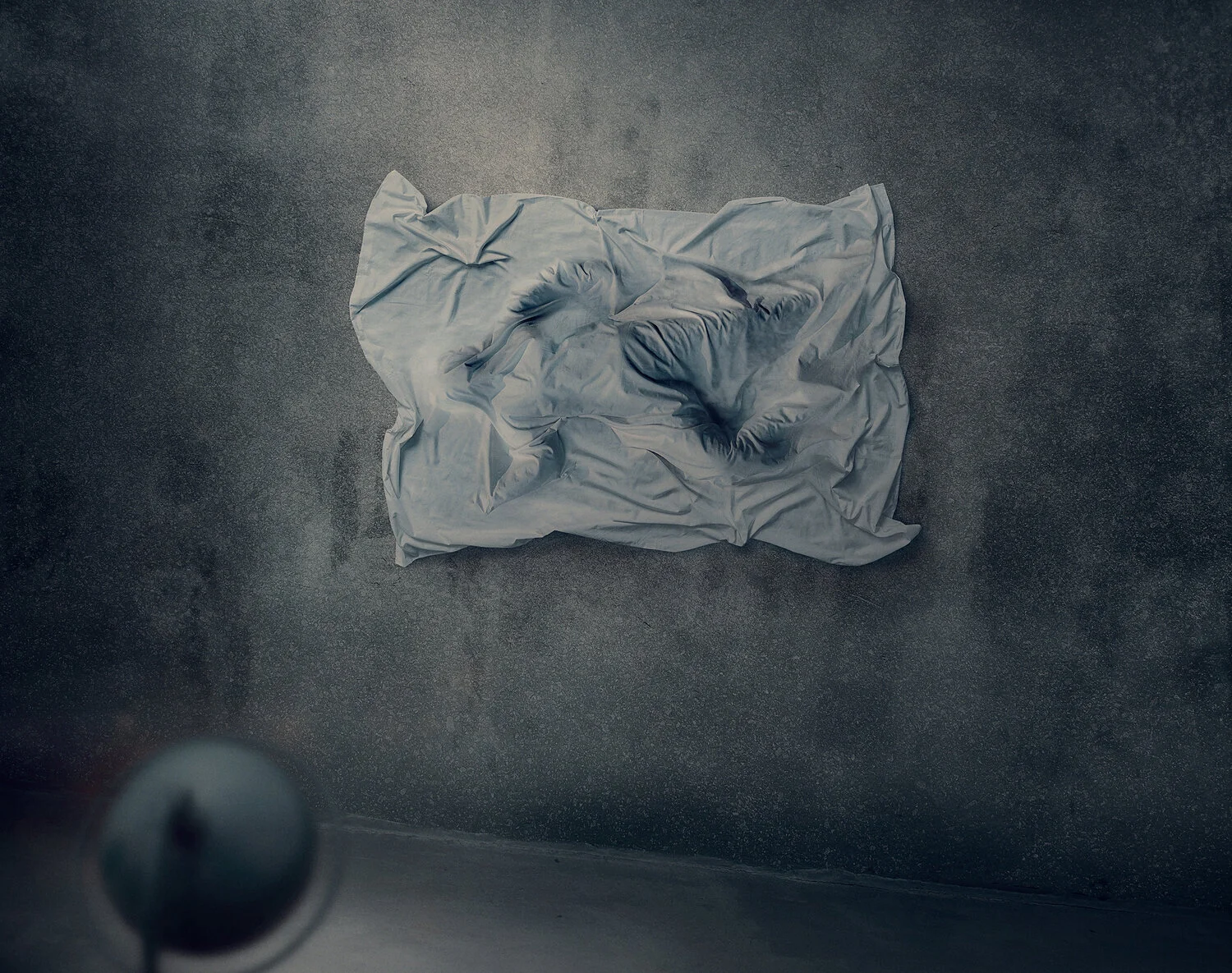A crumpled white bedsheet with a shadowy figure lying on it, on a dark textured floor.