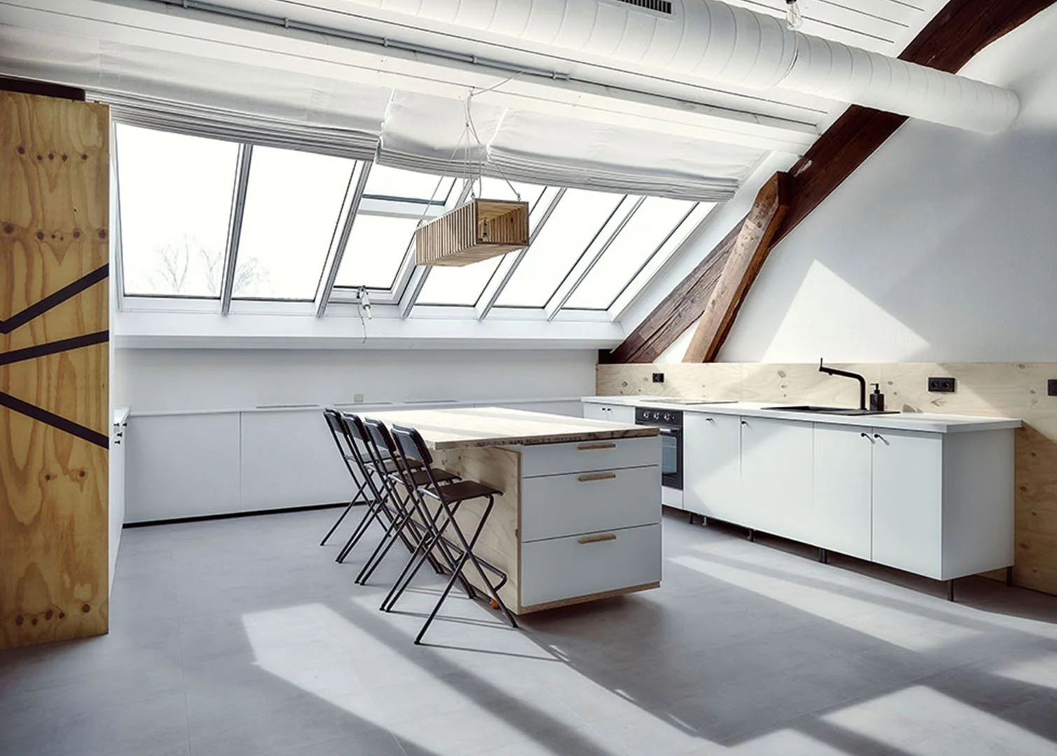 Modern kitchen with white cabinets, a wooden island, and large skylight windows with natural light.