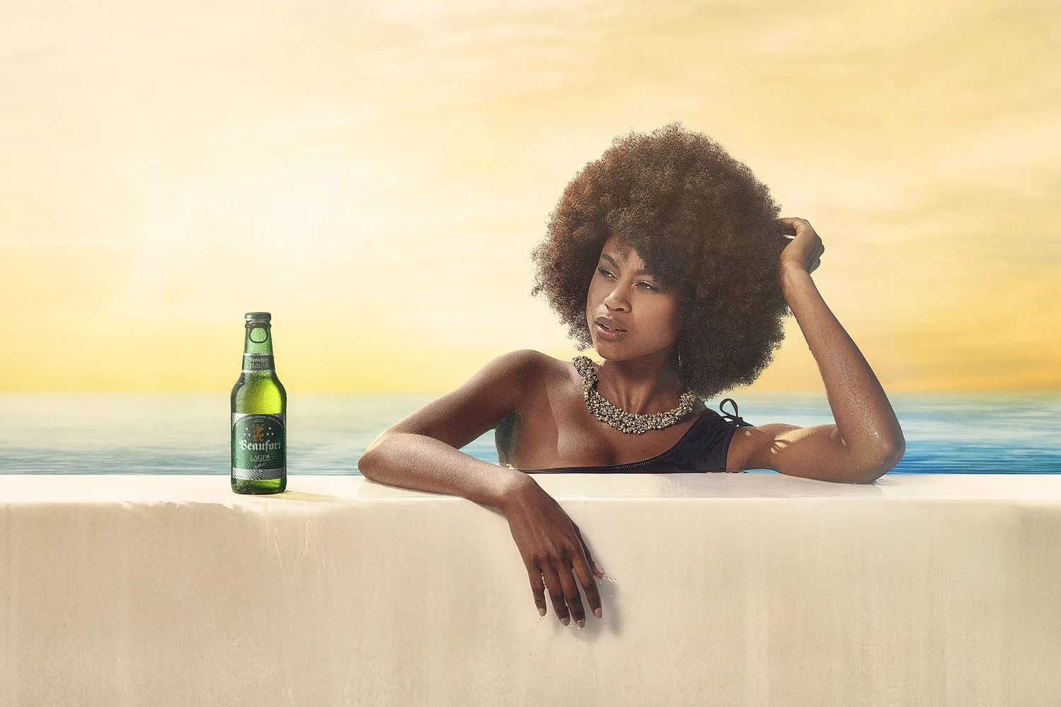 A woman with big curly hair relaxing in a bathtub at sunset, with a green beer bottle on the edge of the tub.