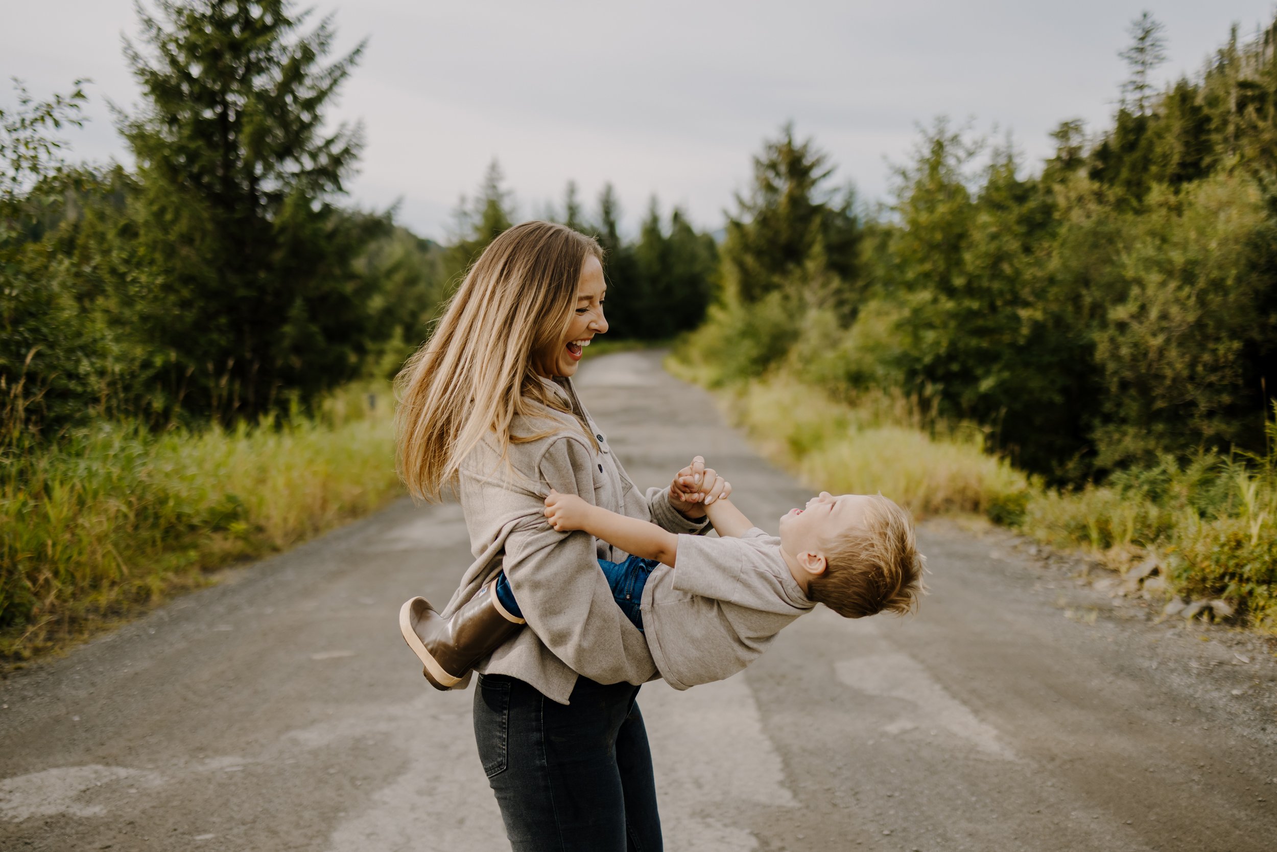 Photo of mother smiling at her son while she spins him around.