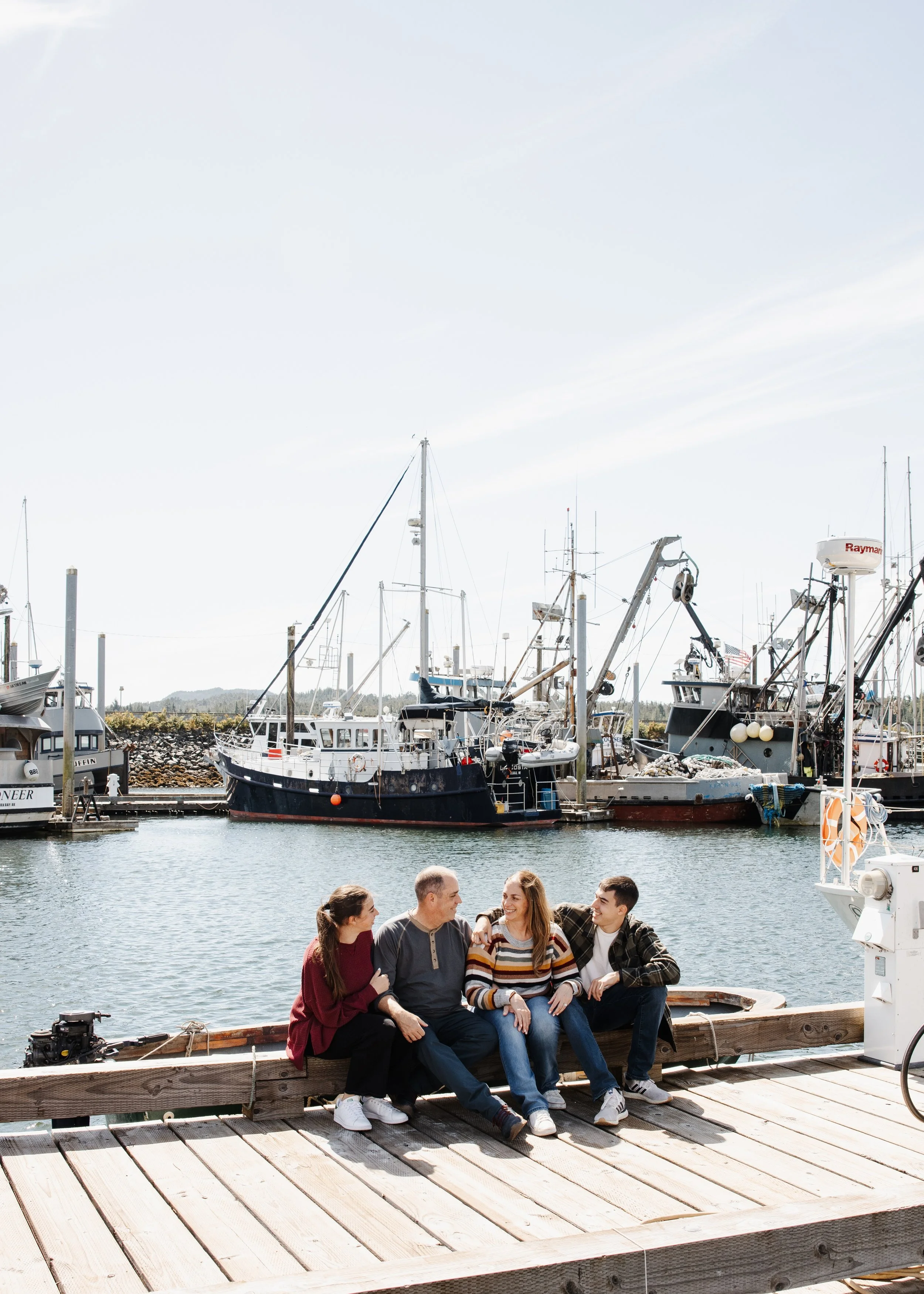 Family sits on a dock in front of boats in Ketchikan Alaska during cruise excursion