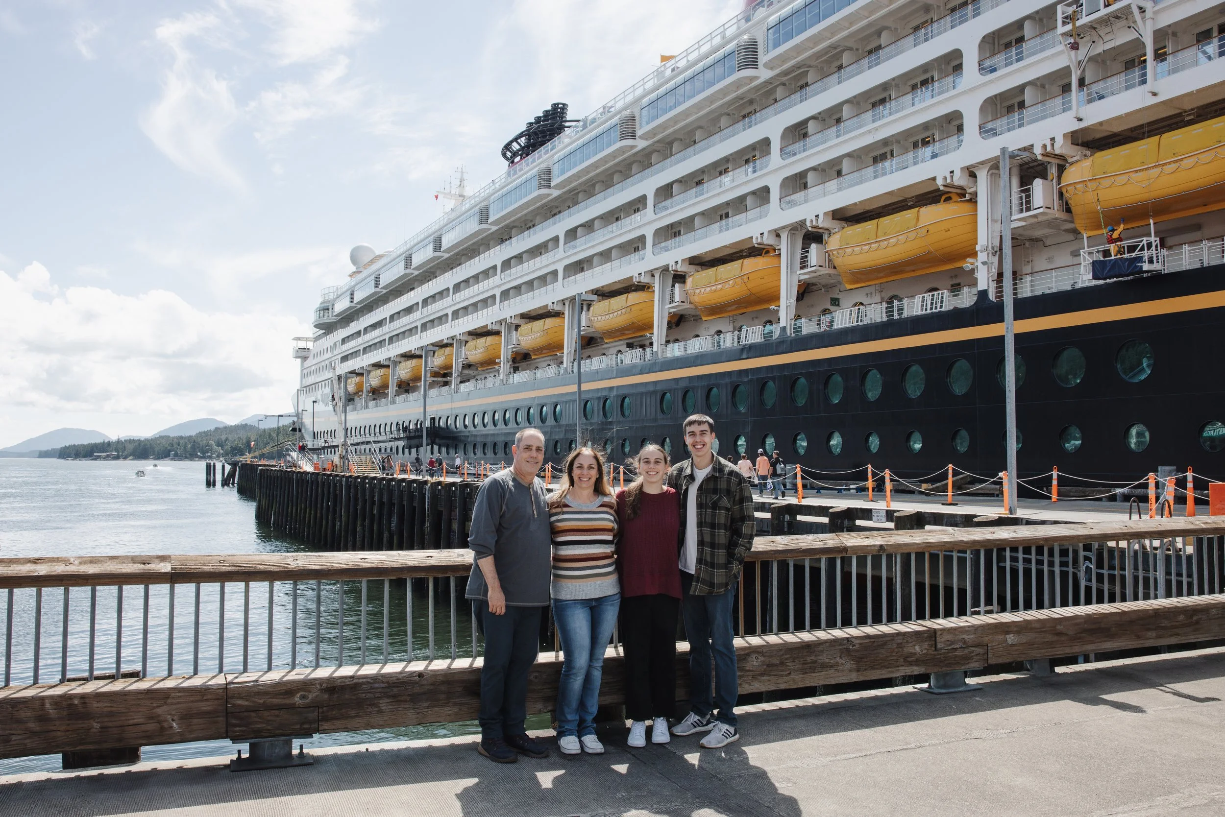 Family stands on a dock in front of Disney Cruise Ship in Ketchikan Alaska during cruise excursion