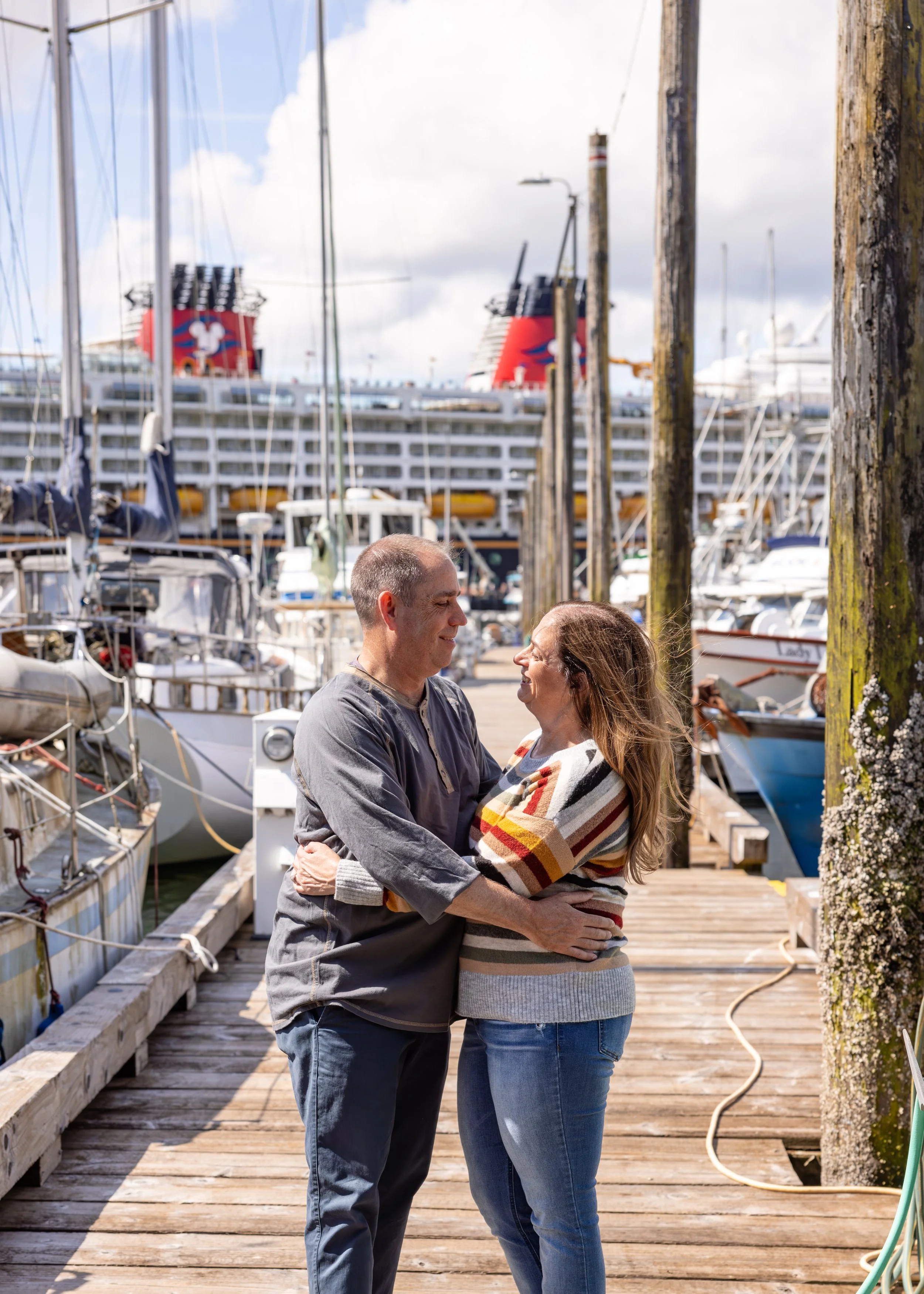 Couple looks into each others eyes while embracing. They are standing on a dock in front of a cruise ship in Ketchikan Alaska.