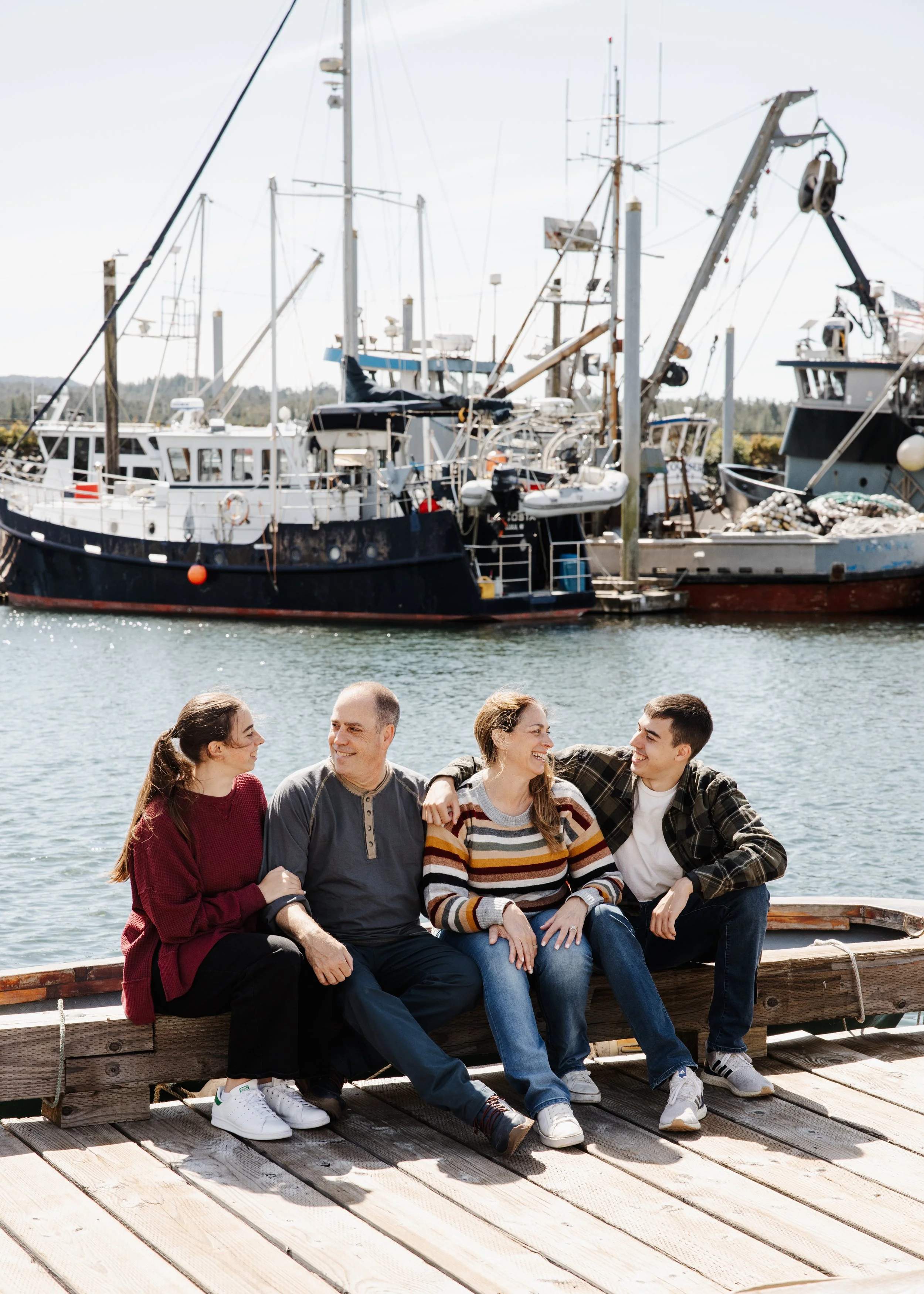 Family sits on a dock in front of boats in Ketchikan Alaska during cruise excursion