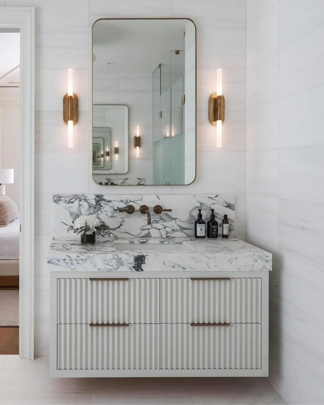 The aesthetic of a wall-mounted faucet feels effortlessly sleek and modern, freeing up counter space while adding a luxurious experience.⁠
⁠
Finished in warm brass, it adds a refined layer of character to this elegant, spa-like space.⁠
⁠
Design by @s