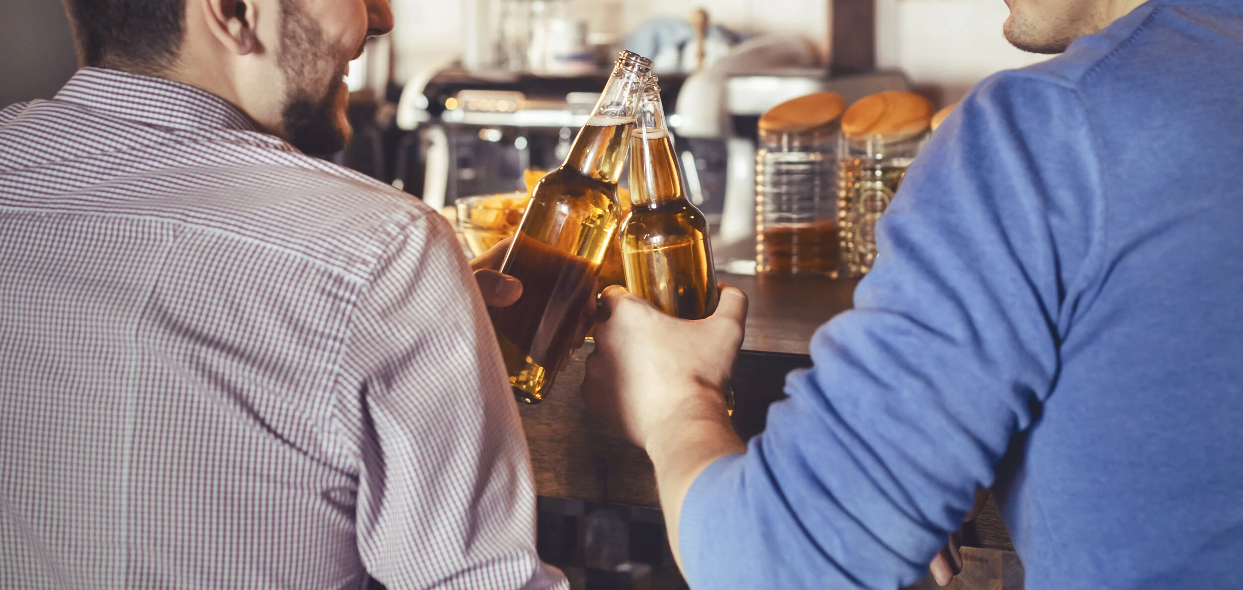 mates-clinking-bottles-of-beer-in-pub-XBHUEED.jpg