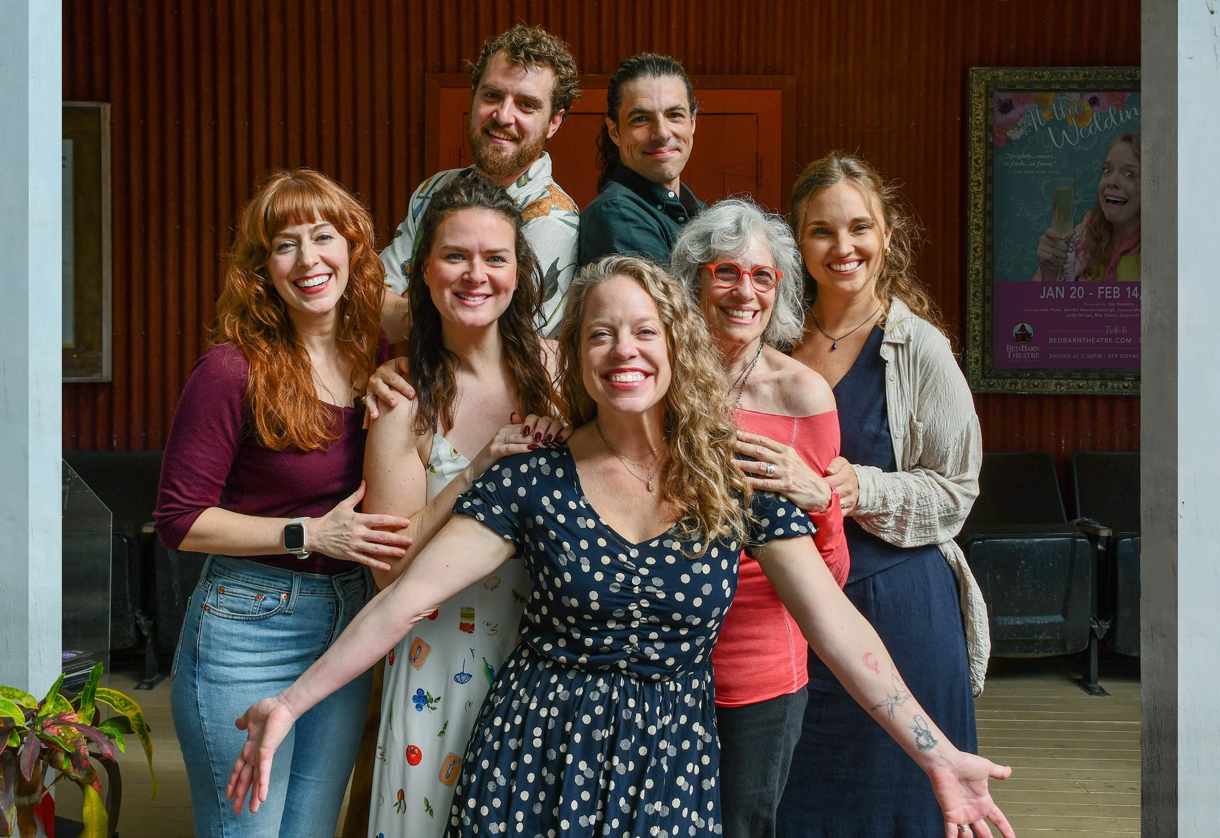 group of men and women standing together in a group in front of a red building