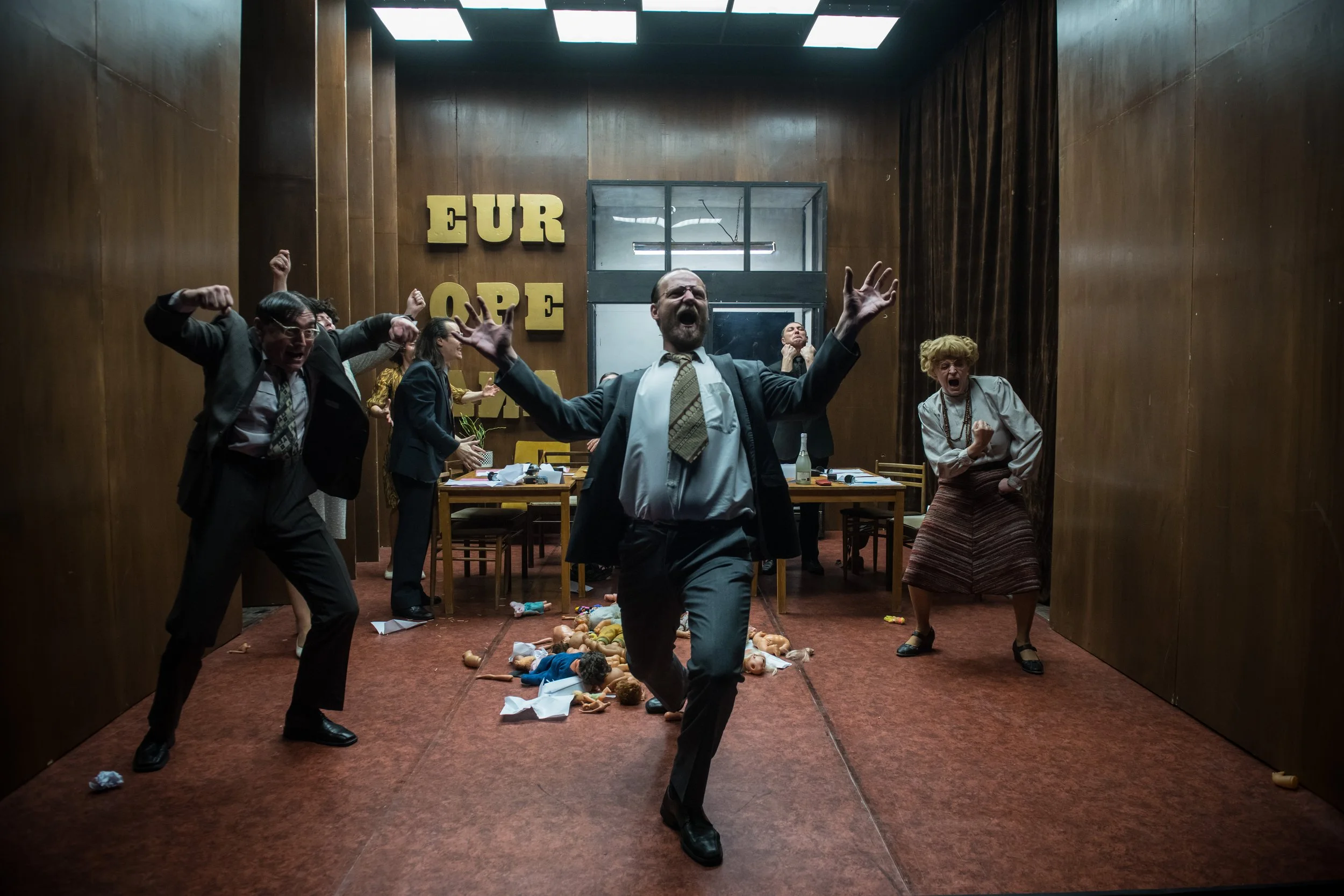 Actors captured moving energetically on a retro stage, in an office like scene set up.