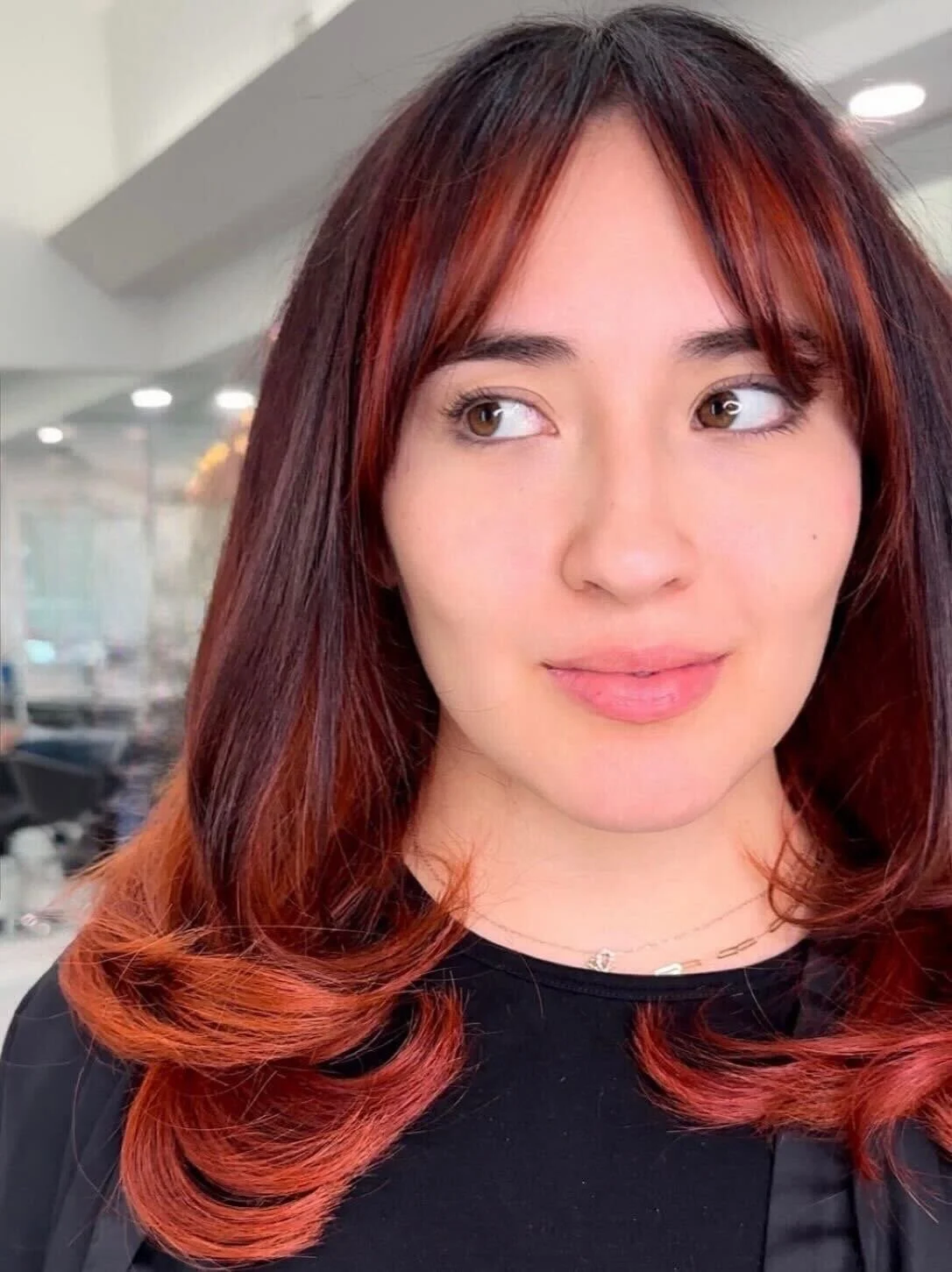 Fiery red layered haircut with curtain bangs at Bellibone Salon in Maywood, NJ.