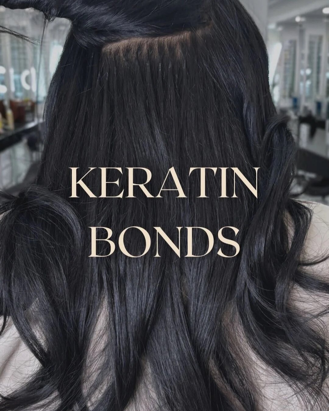 Seamless hair extension blend at Bellibone Salon Maywood NJClose-up of long, shiny black hair with curls, featuring a top section showing a hair part. Text overlay reading 'Keratin Bonds'.