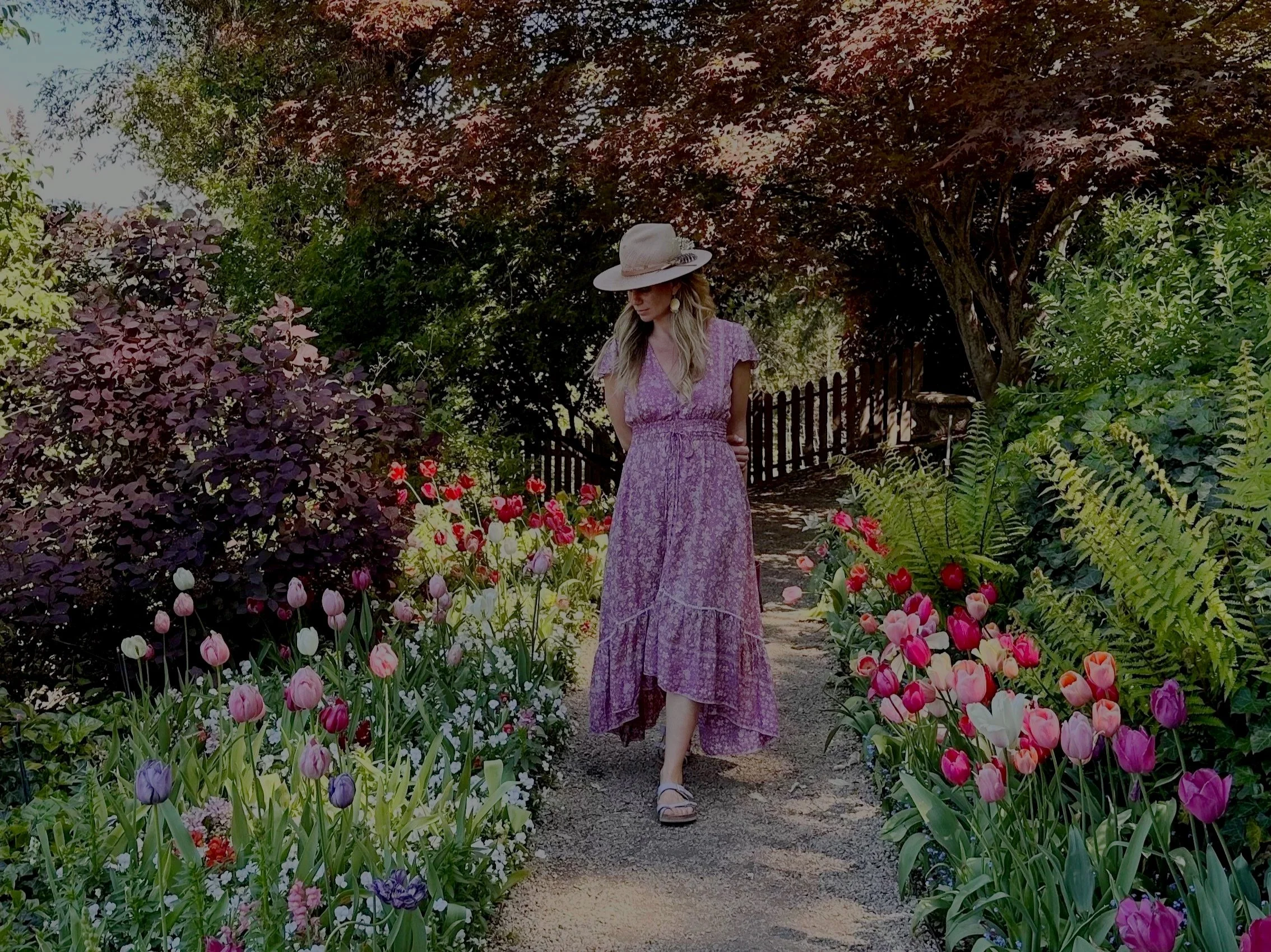 Kadhi Bo in a dress and sunhat walking in a manicured garden of blooming flowers, with her newsletter sign-up for below it.
