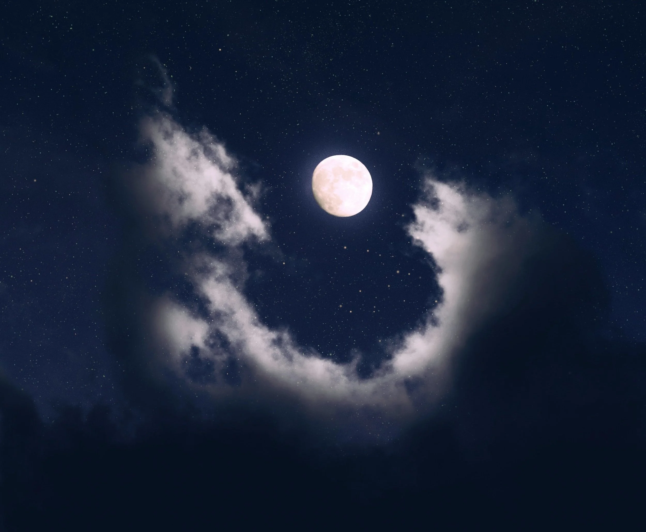 nearly full moon against midnight blue starry sky framed by clouds