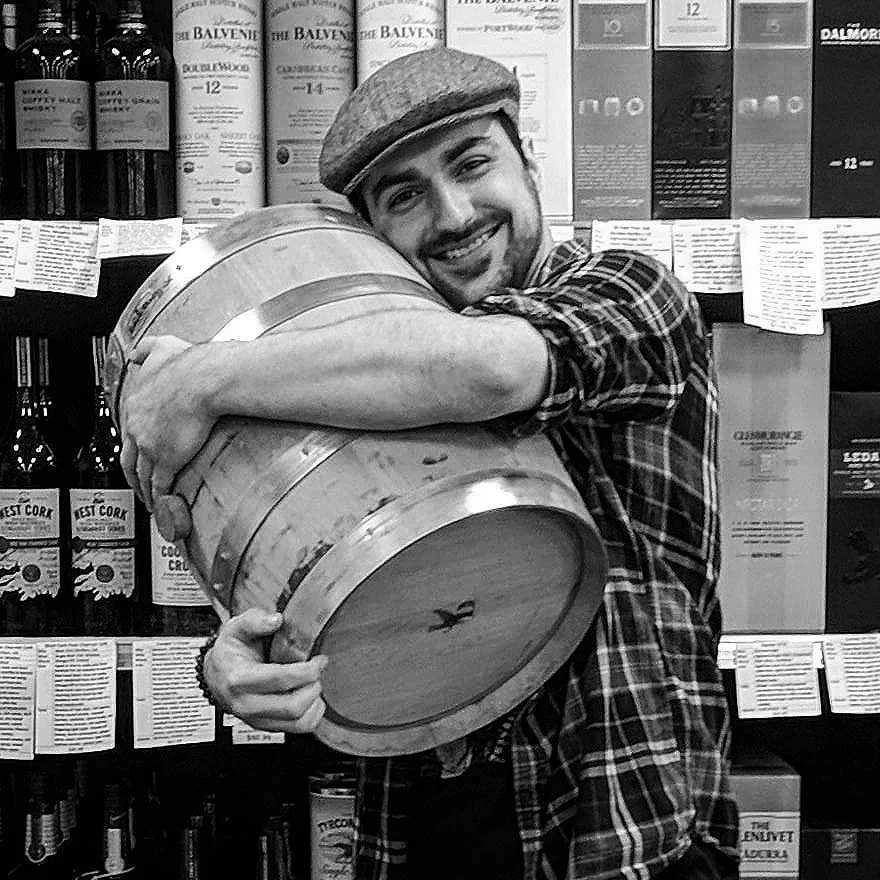 George hugging a barrel of Journeyman Distillery’s Silver Cross that he selected for Parkway Wine & Liquor in front of the ‘Great Wall of Whiskey’