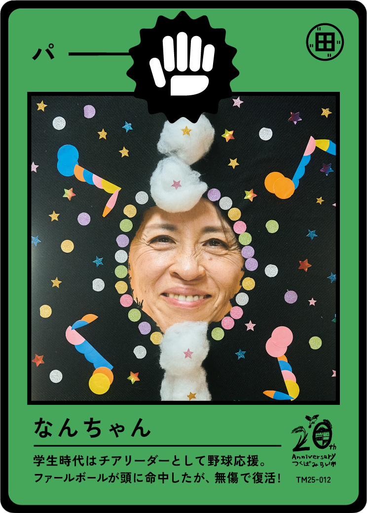 A woman with a smiling face surrounded by colorful party decorations, cotton balls, and star-shaped confetti on a black background, enclosed in a green frame resembling a playing card or badge.