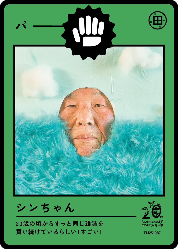 A humorous card with a man's face and a fluffy blue background. The card has a green border, a black fist icon at the top, and Japanese text. It celebrates an anniversary and mentions buying a magazine since around age 20.