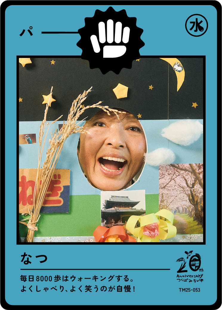 A person smiling with their face in a circular cutout of a decorative display featuring paper craft stars, clouds, and a photo of a traditional Japanese building, with Japanese text at the bottom.