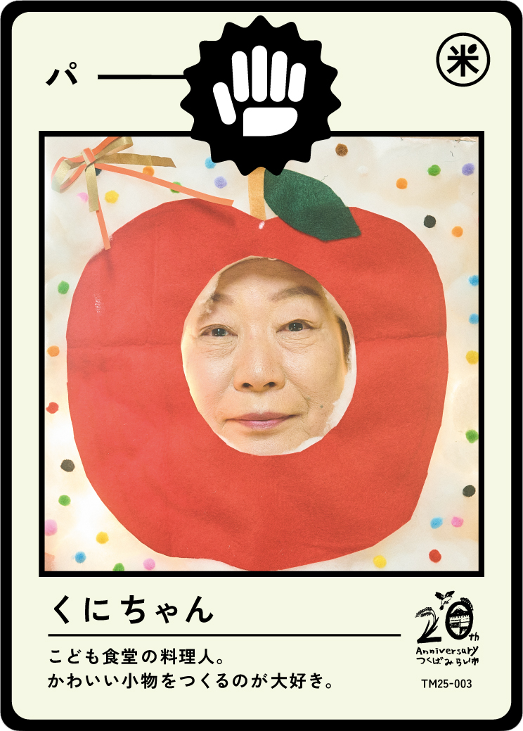 Person's face poking through a paper cutout of an apple with confetti and a decorative bow around it.