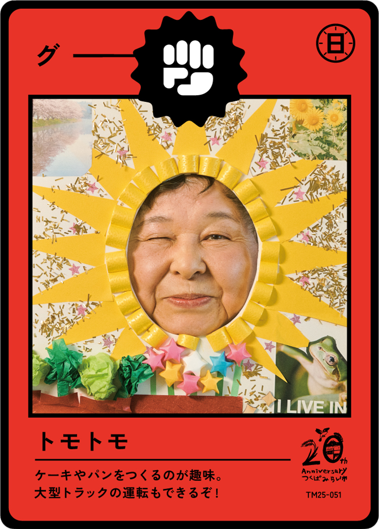 Photo of a woman with one eye closed, framed by a yellow paper sun with rays made from rolled yellow paper and colorful stars. The background is decorated with various patterns, including flowers and animals. Red border with Japanese text and a logo 