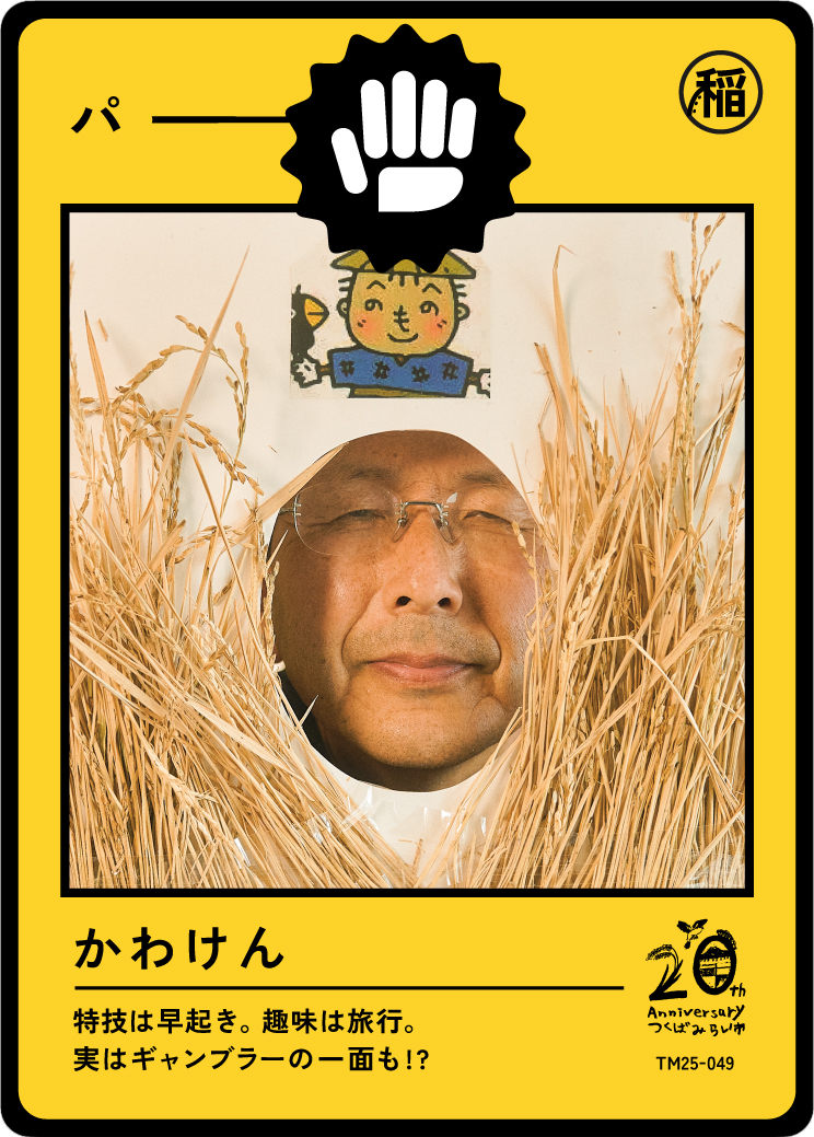 A person smiling with a face cutout in a straw display with Japanese text and illustrations, resembling a playful corn or wheat-themed photo prop.