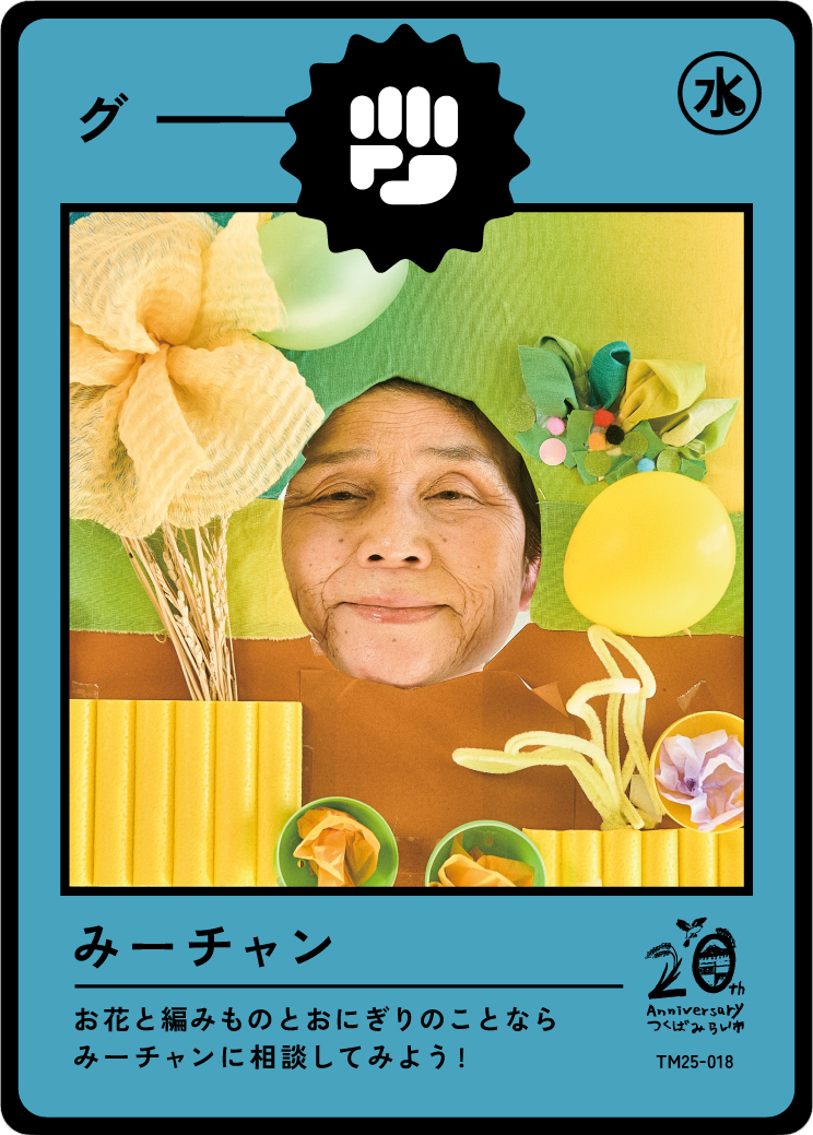 A colorful mixed media collage featuring a person's face surrounded by various craft materials like paper flowers, balloons, and textured paper, arranged to resemble a card or artwork.