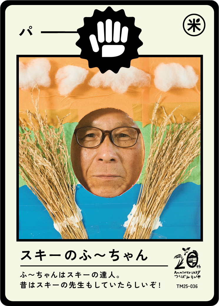 A collage featuring a person's face with glasses, surrounded by wheat stalks and painted clouds, resembling a playing card or poster, with Japanese text and a logo celebrating a 20th anniversary.