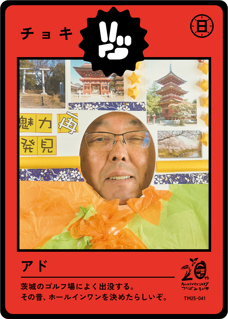 A person peeking through a hole in a board decorated with Japanese-themed images and decorations, resembling a Japanese trading card or game card. The card features images of traditional Japanese architecture, a torii gate, and cherry blossoms, with 