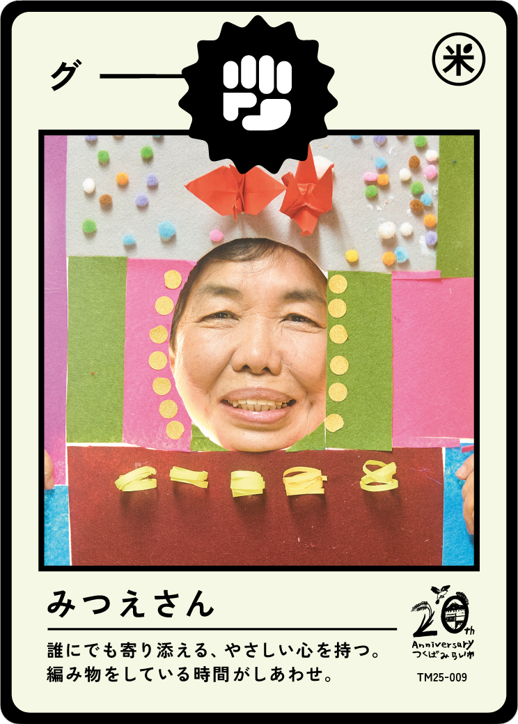 A person with a happy face in a paper craft photo frame decorated with colorful paper and origami butterflies, surrounded by small pom-poms and paper strips.