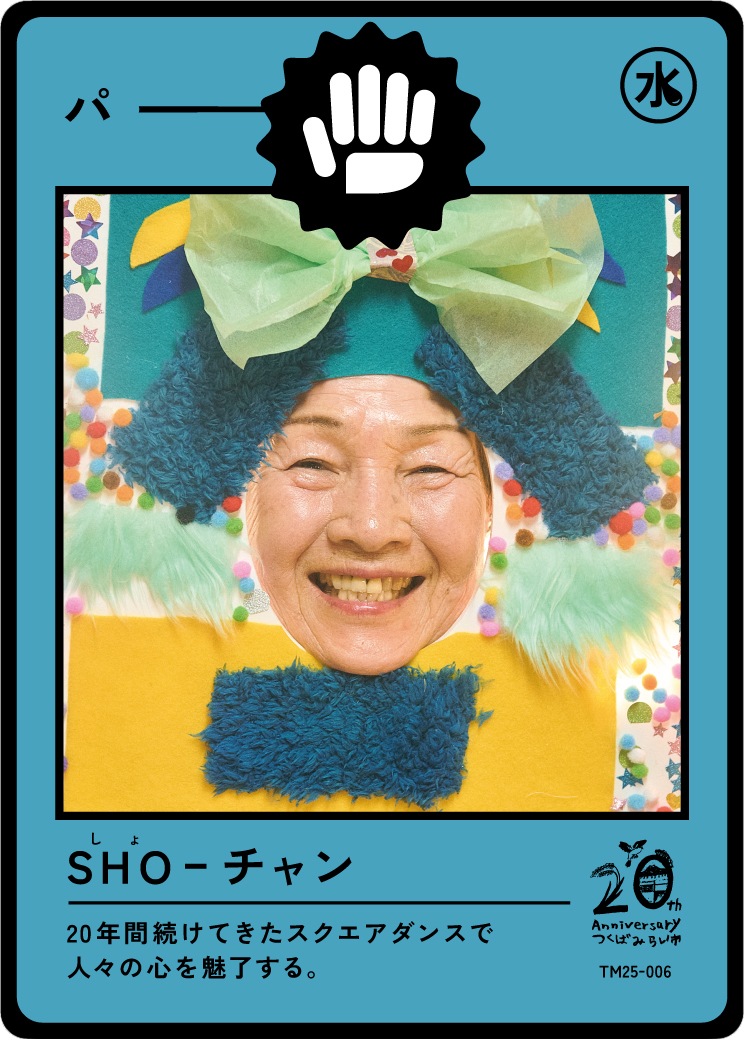 A person with a smiling face wearing a colorful costume with fluffy materials, a large bow, and surrounded by decorative elements, resembling a playful or festive attire.