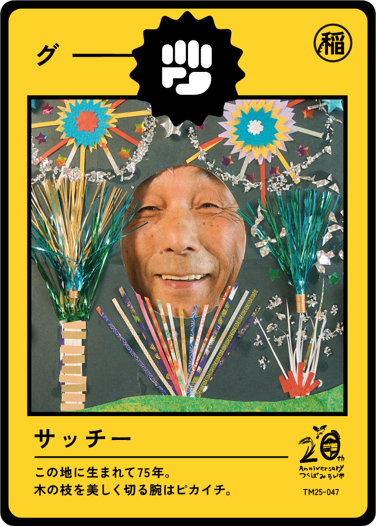A celebratory card featuring a man's face with decorations including fireworks, colorful paper strips, and stars. The card is yellow with Japanese text and symbols indicating a 75th birthday celebration.