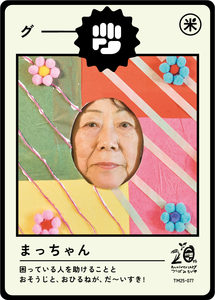 A colorful handmade card with a cutout of a woman's face, surrounded by paper flowers and pom-poms, with Japanese text and decorations celebrating a 20th anniversary.
