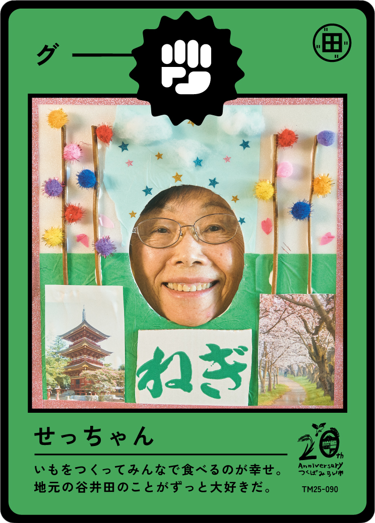 A decorated display with a person's smiling face through a cut-out, framed by colorful pompoms, with images of a pagoda and cherry blossoms, and Japanese text celebrating a 20th anniversary.