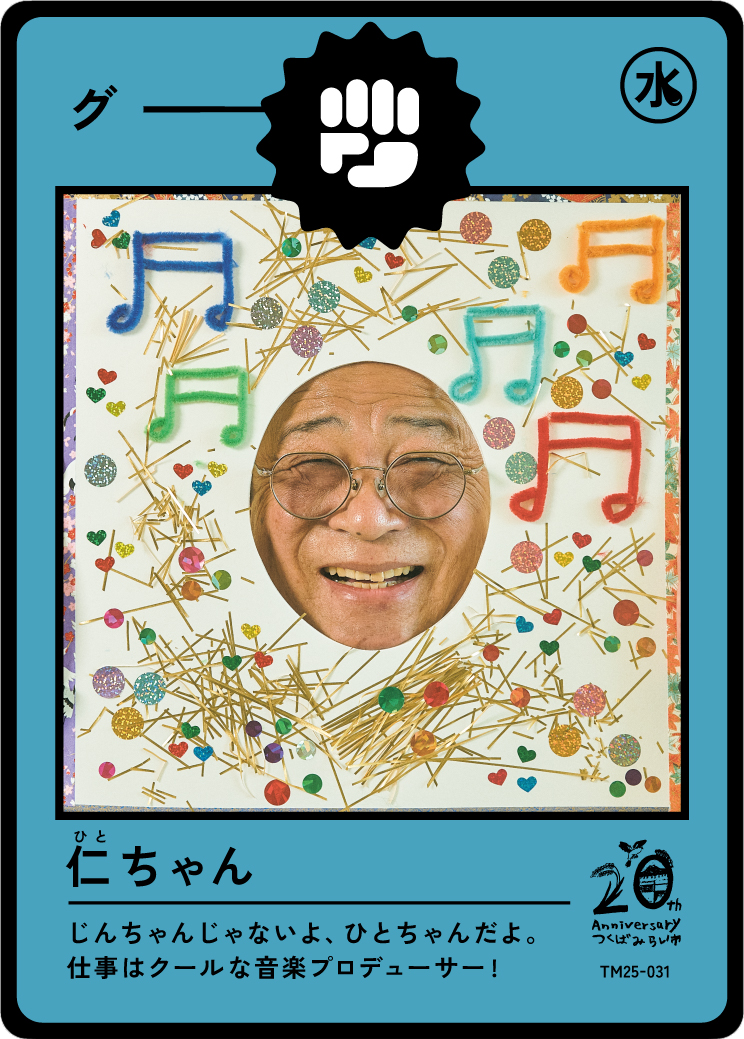 A man with glasses smiling through a photo cutout on a colorful card decorated with musical notes, confetti, and sticks, celebrating an anniversary.