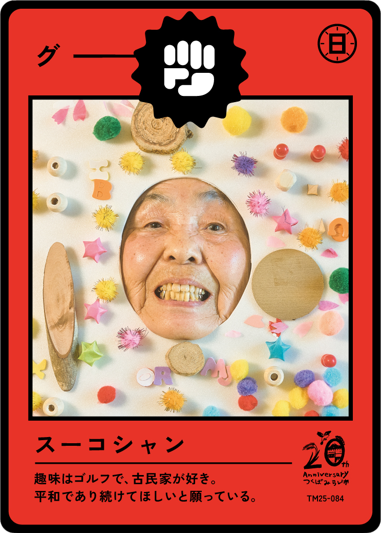 A playful collage with a smiling elderly woman’s face in a circular cutout, surrounded by colorful craft materials including pom-poms, paper shapes, and wooden pieces, on a white background. The image is styled like a vintage Japanese game or trading