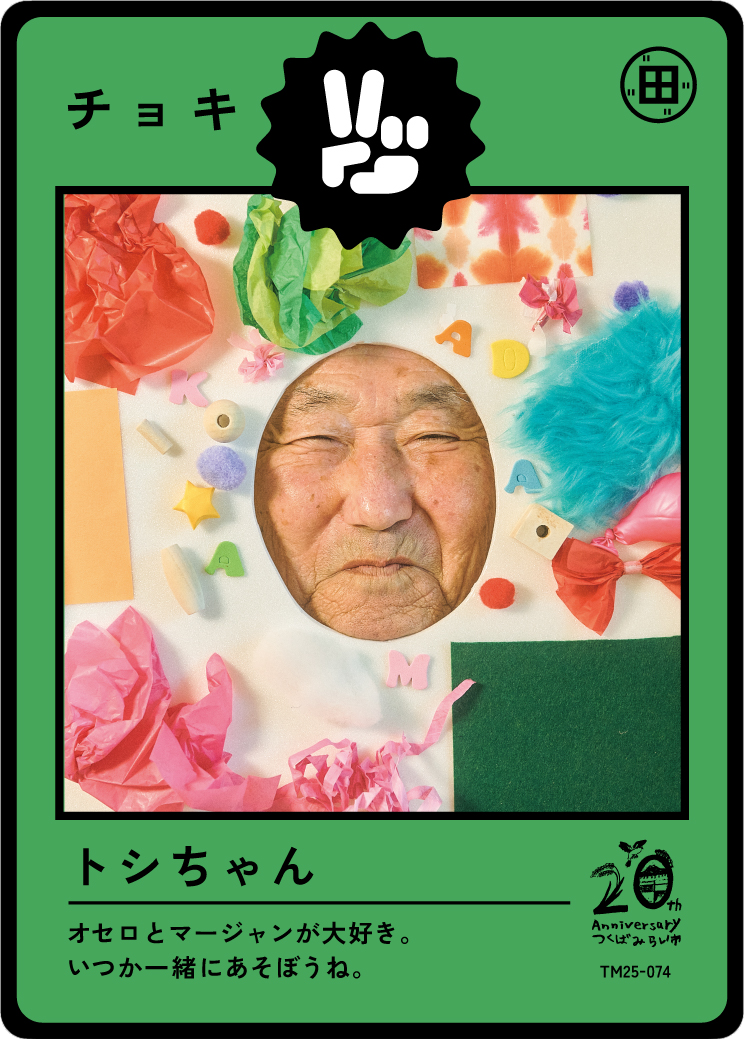 A playful card with a person's face peeking through a circular cutout, surrounded by colorful tissue paper, foam shapes, and small decorative items, celebrating a birthday or special occasion.