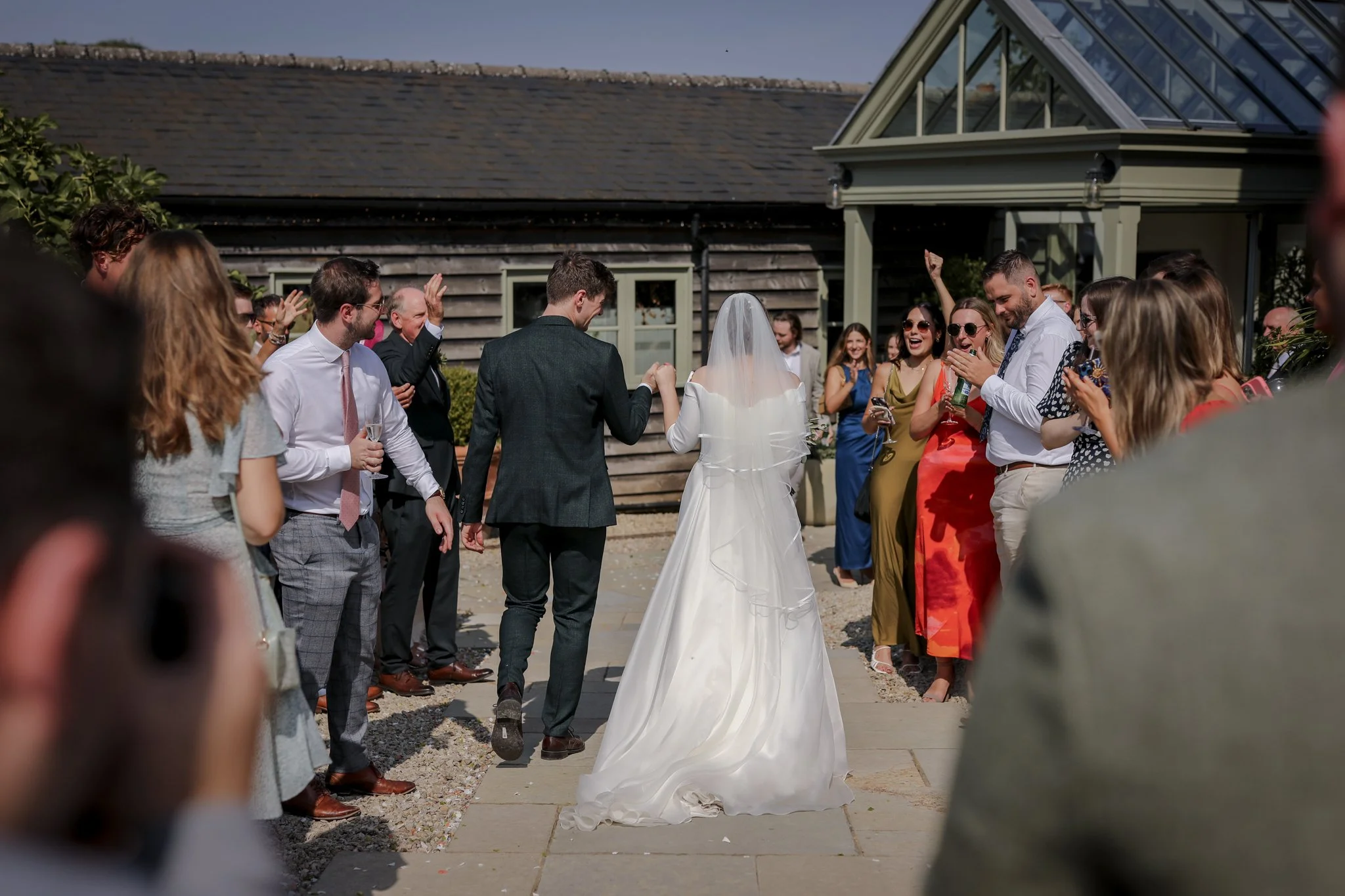 A bride and groom walking hand in hand during their outdoor wedding ceremony, surrounded by joyful guests.