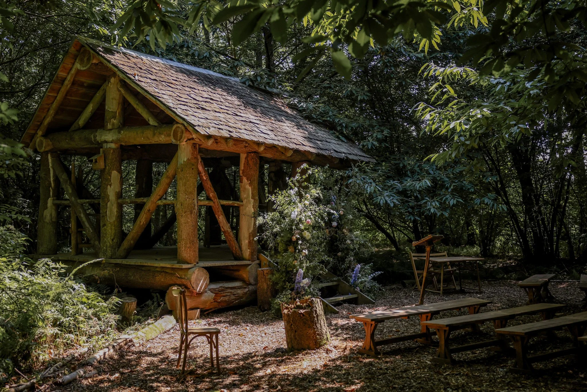 A wooden treehouse elevated among lush green trees with sunlight filtering through the leaves.
