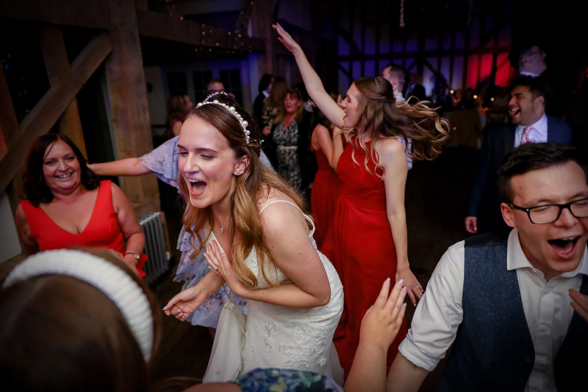 People dancing and celebrating at a lively party or wedding reception, with joyful expressions and animated movements.