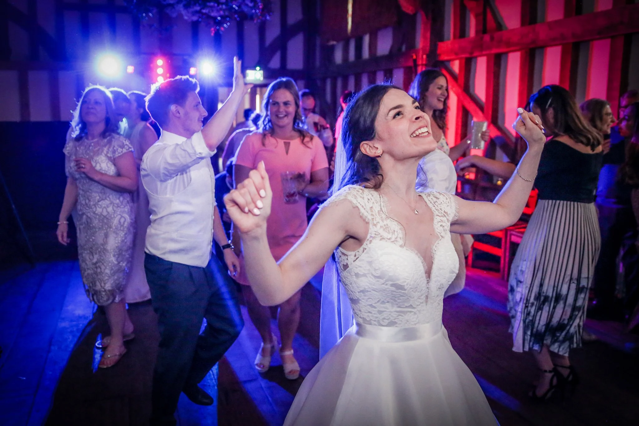 People dancing and enjoying music at a celebration or party with colorful lighting.