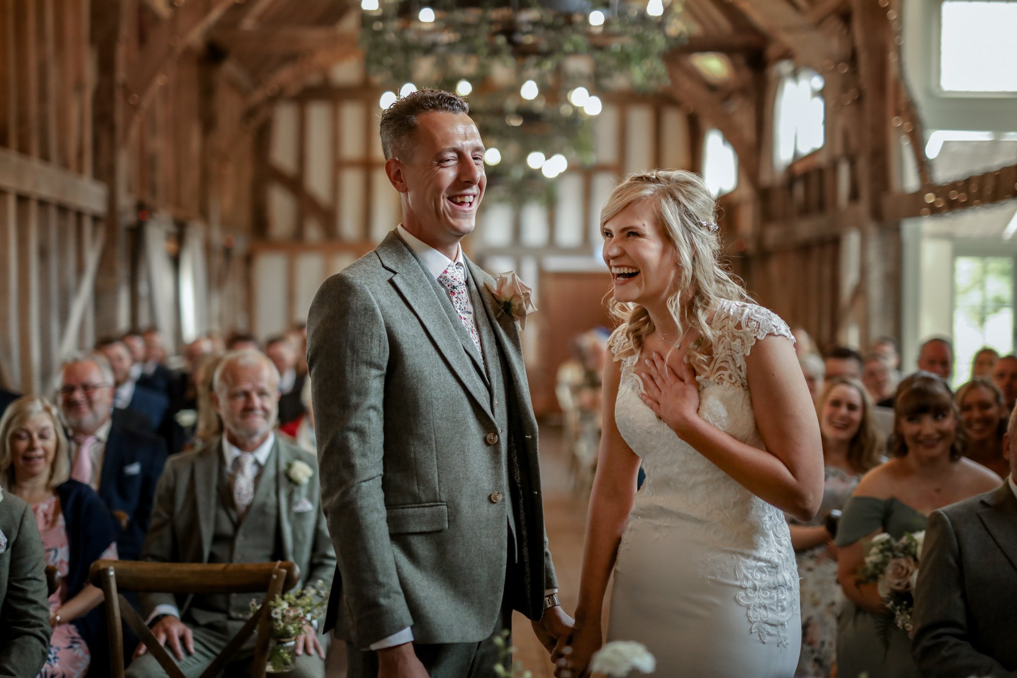 A bride and groom sharing a moment during their wedding ceremony inside a rustic wooden venue, surrounded by family and friends.